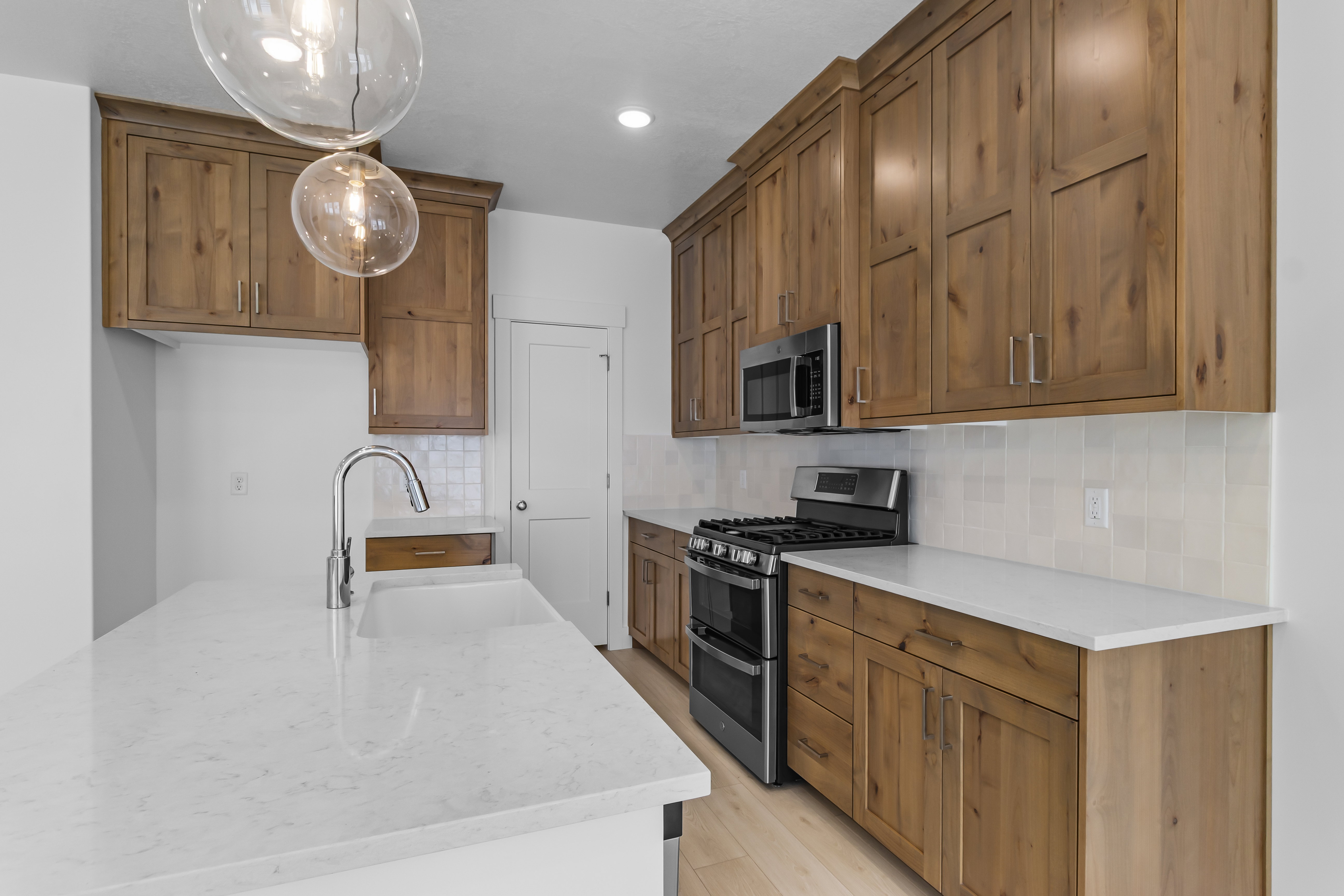 Open-concept kitchen featuring wood cabinetry, light-toned countertops, and a subway tile backsplash