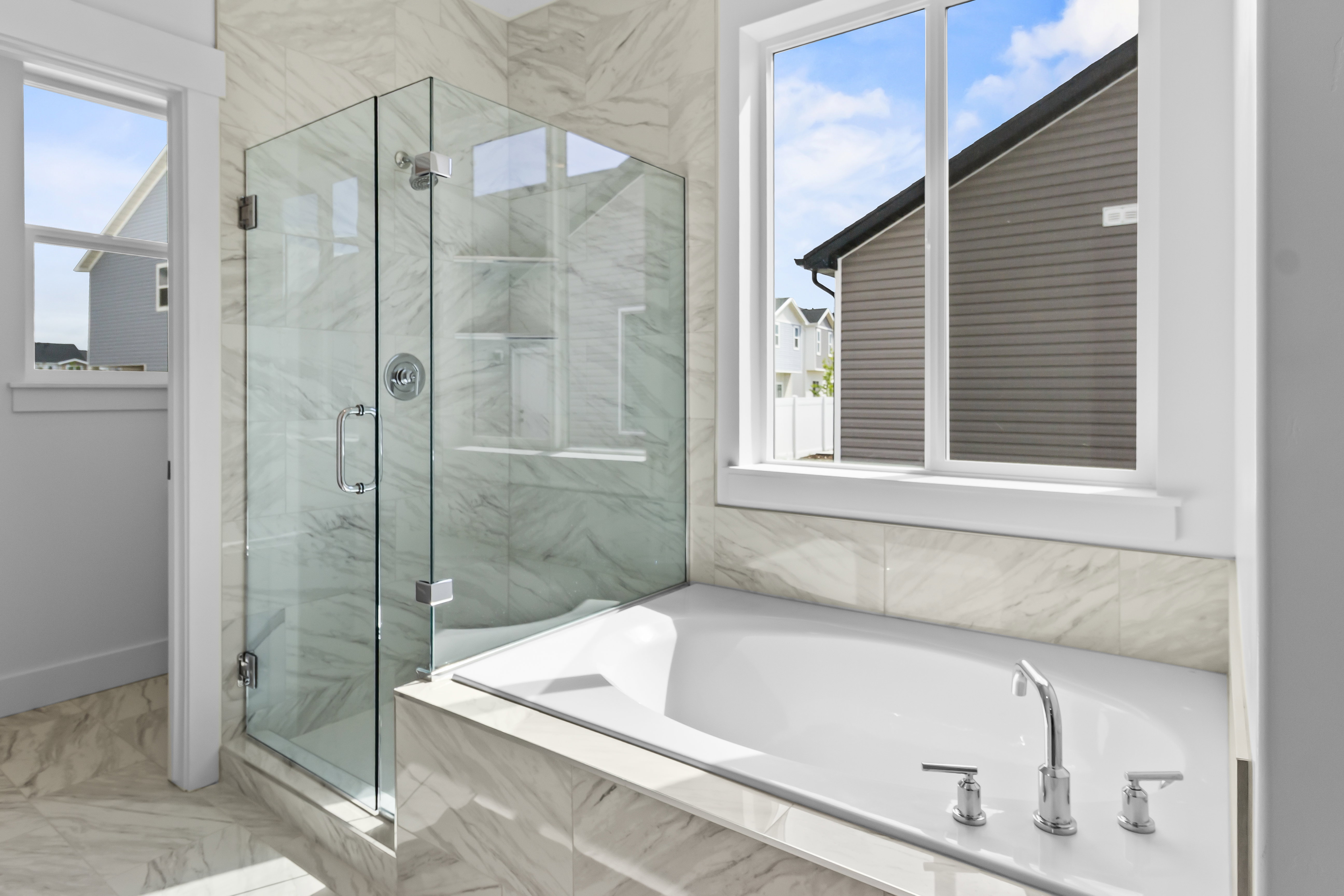 Built-in bathtub with chrome fixtures, glass-enclosed shower, and full-height tiled walls