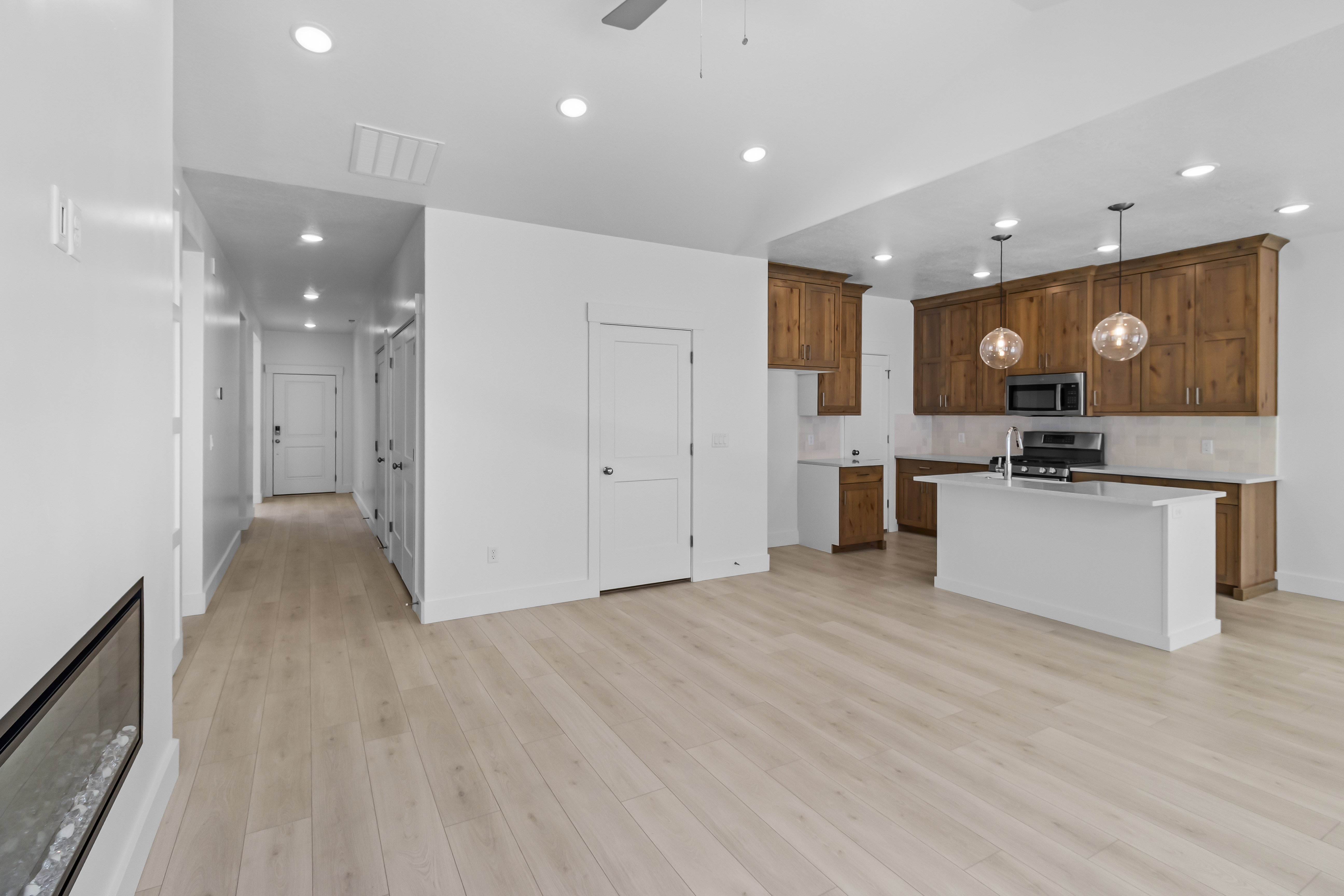 Open-concept living area featuring light wood-finish flooring and a contemporary linear fireplace