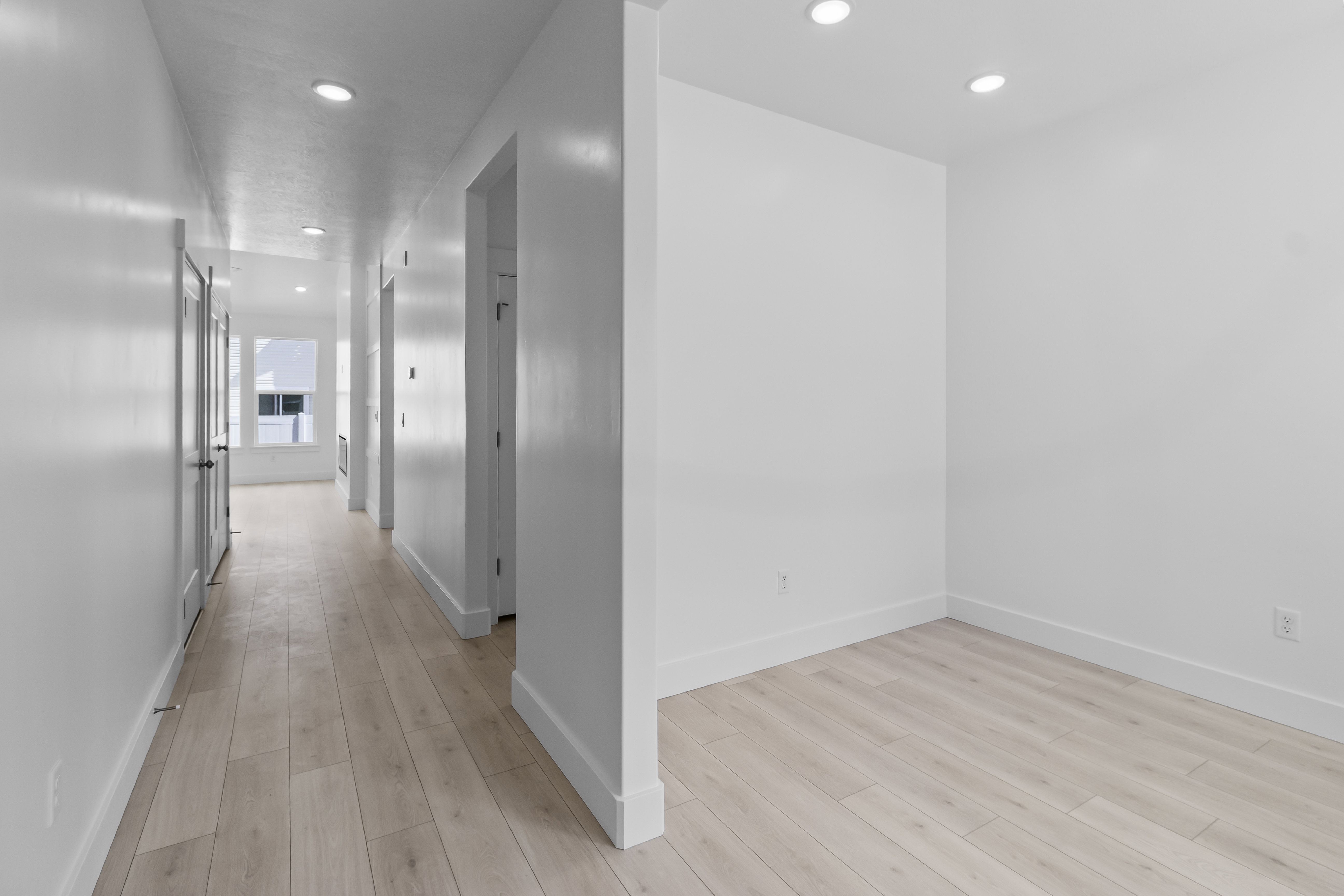 Hallway featuring light wood-finish flooring, recessed ceiling lighting, and white baseboards