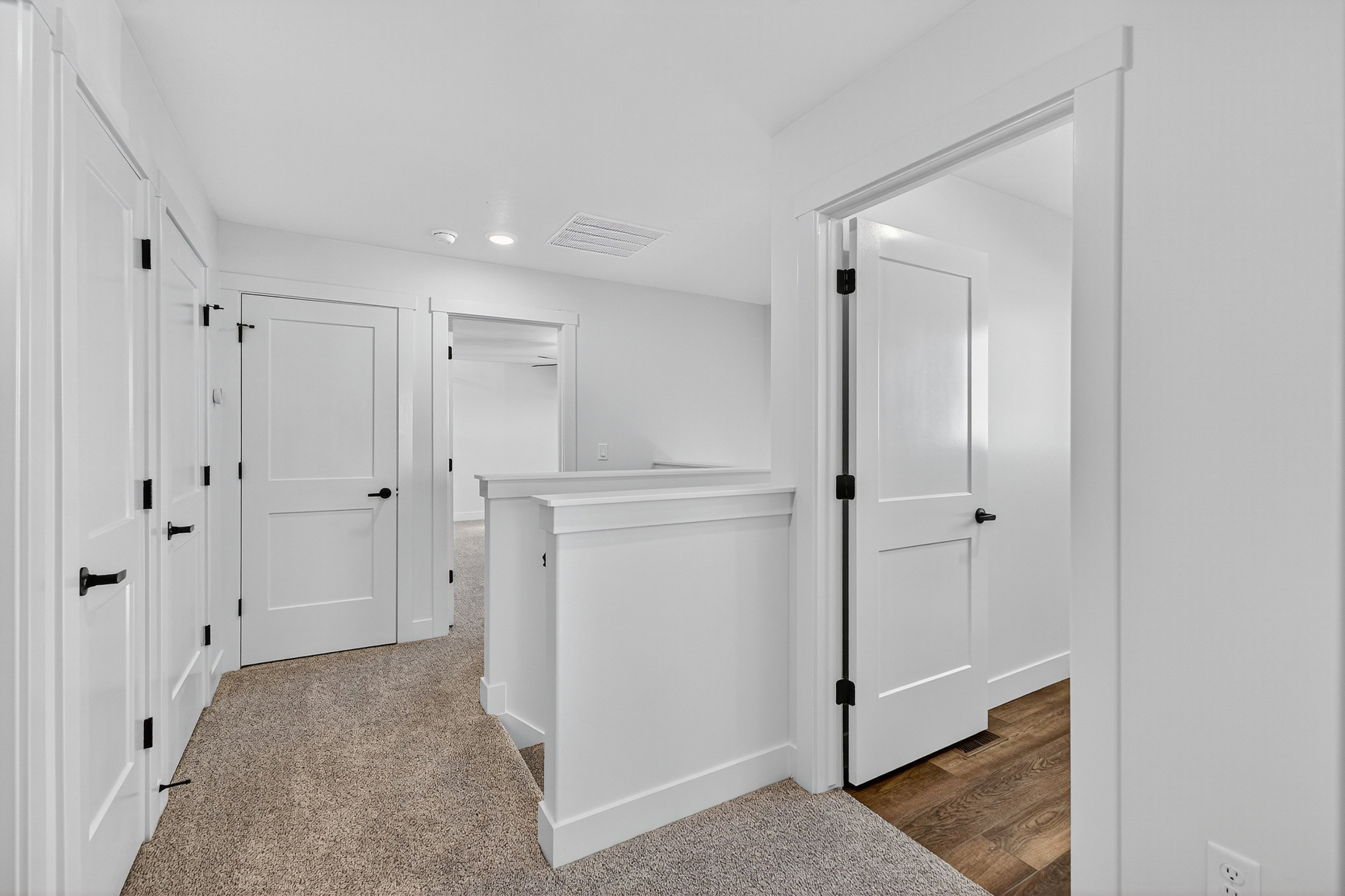 Hallway with light-colored carpeting, white walls, and white trim