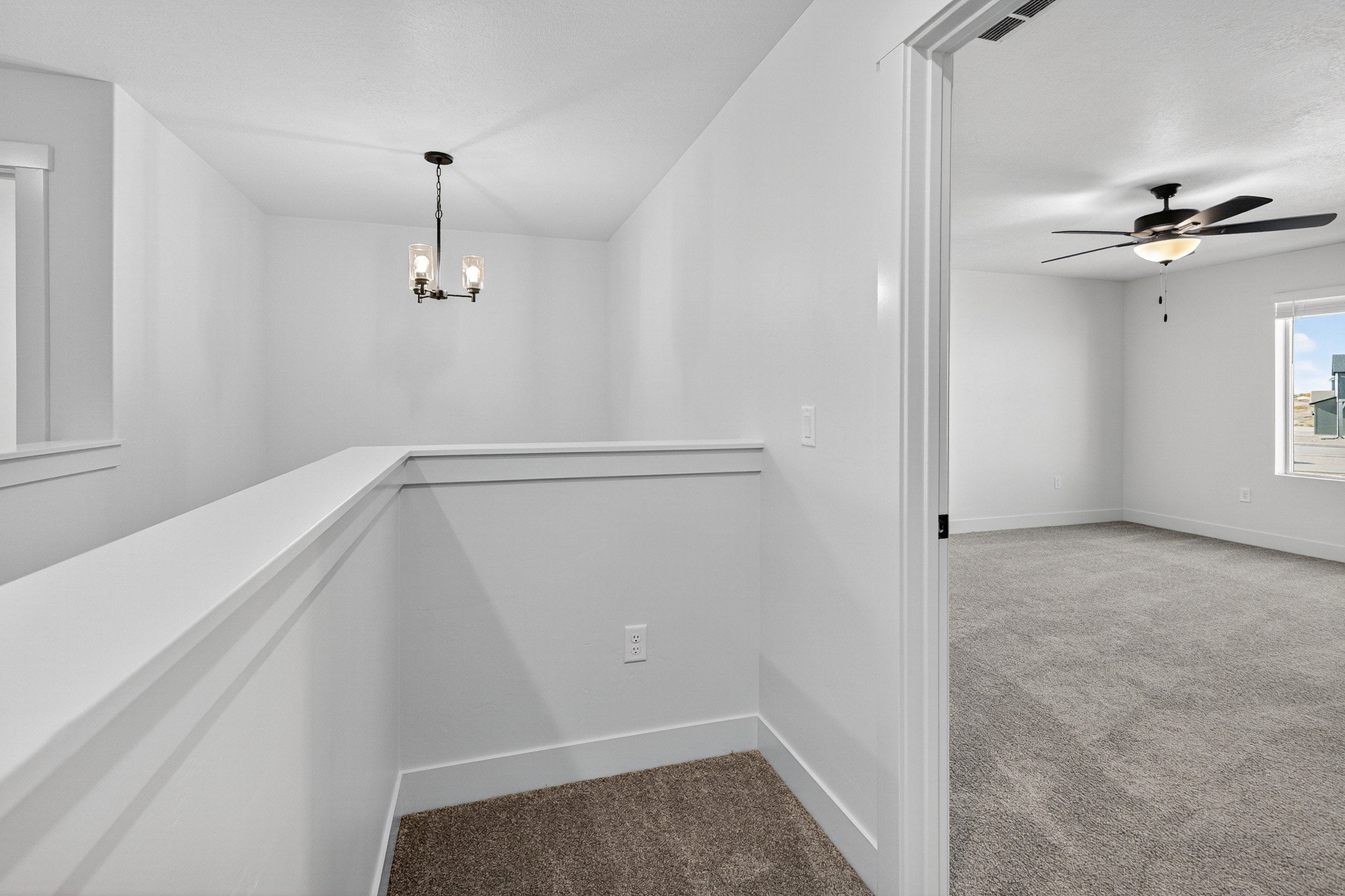 Upper-level landing featuring a contemporary chandelier, white wall finishes, and a neutral carpeted floor