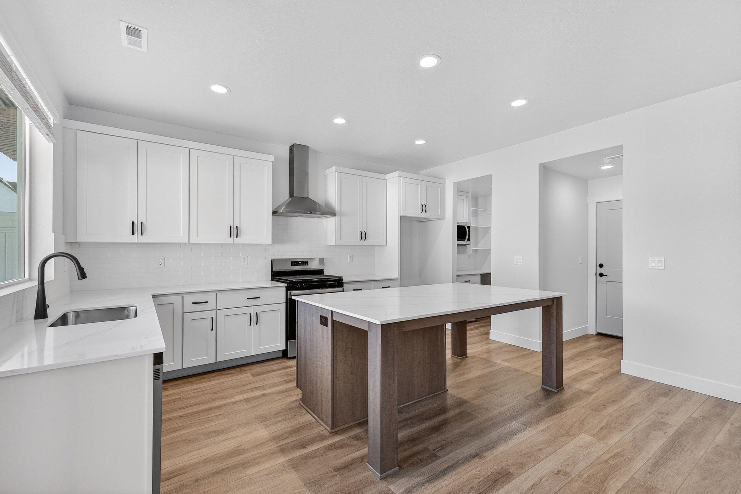 Contemporary kitchen featuring white shaker cabinetry, light-toned wood-finish flooring, and recessed lighting