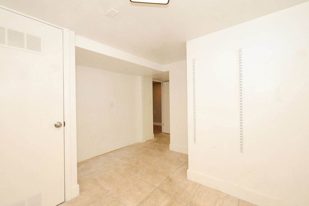 Neutral-toned tile flooring, white walls, and a white door with a silver knob