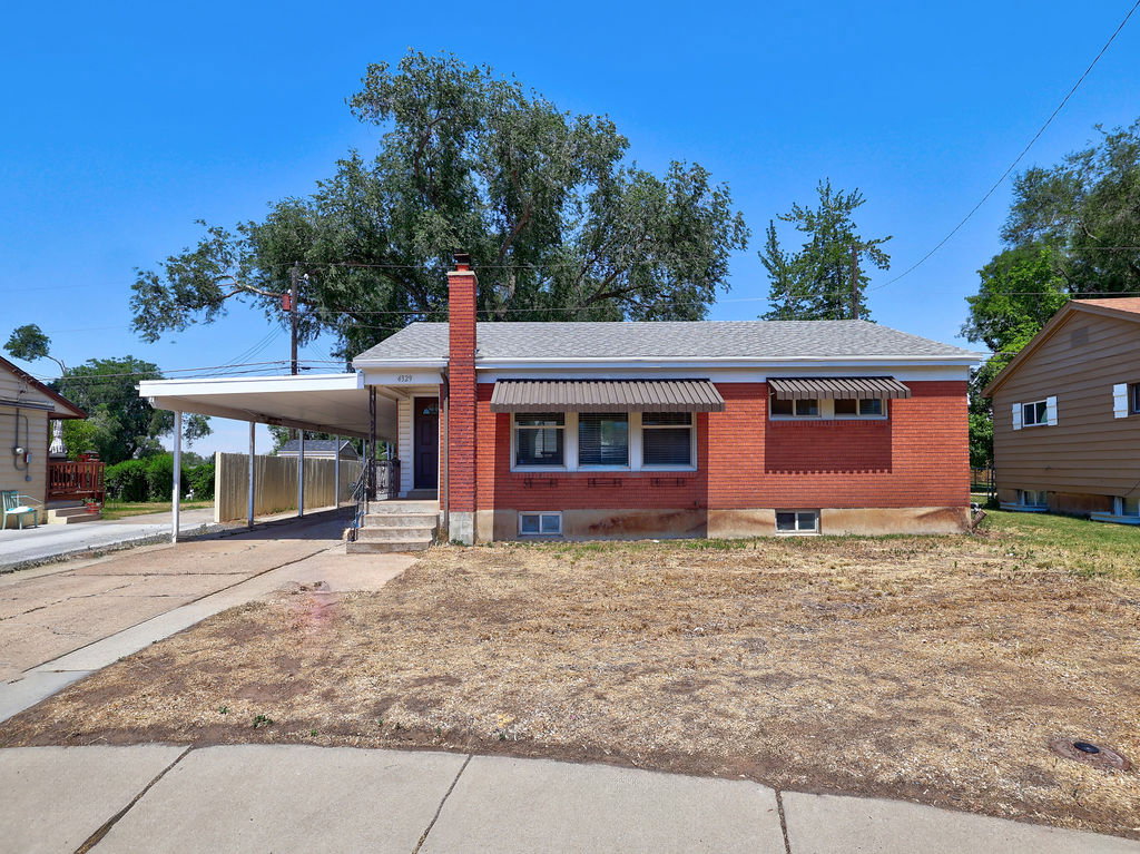 Brick facade residence featuring a covered carport, front porch, and multiple window awnings