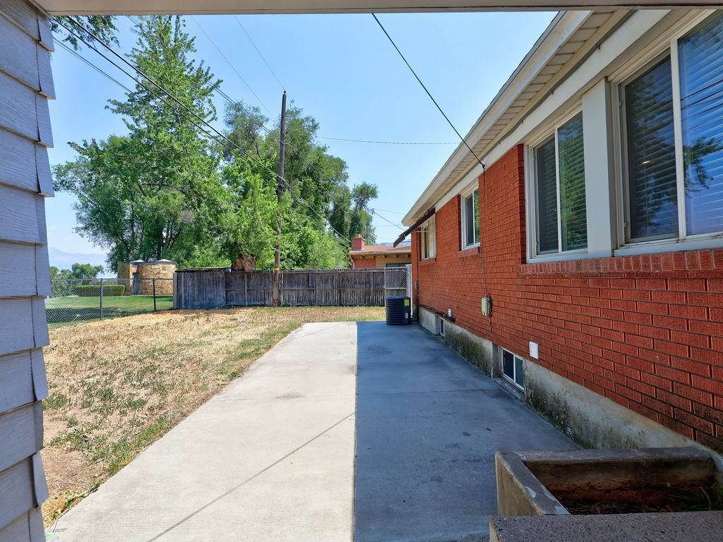 Exterior brick facade with multiple windows, featuring an expansive concrete patio and partially fenced yard