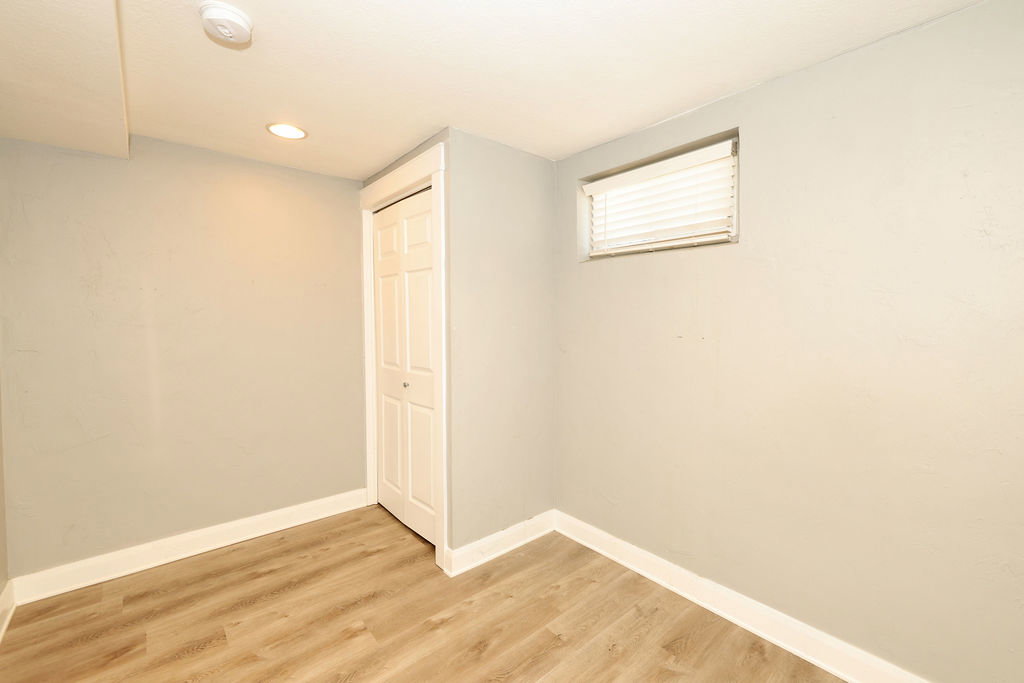 Room featuring light-toned wood-finish flooring, neutral gray walls, and white baseboards