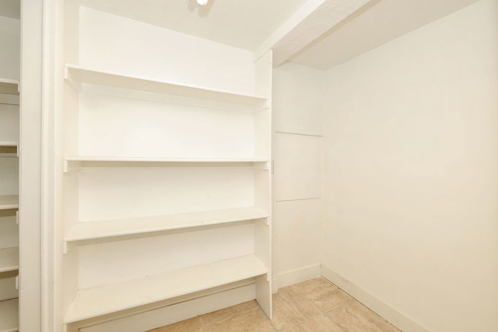 Built-in shelving providing extensive storage, neutral wall paint, and light-toned floor tiling