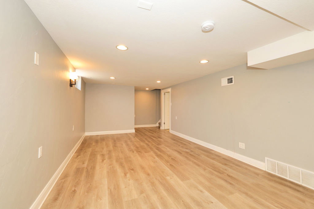 Expansive open room featuring wood-finish flooring, recessed lighting, and light gray walls with white trim