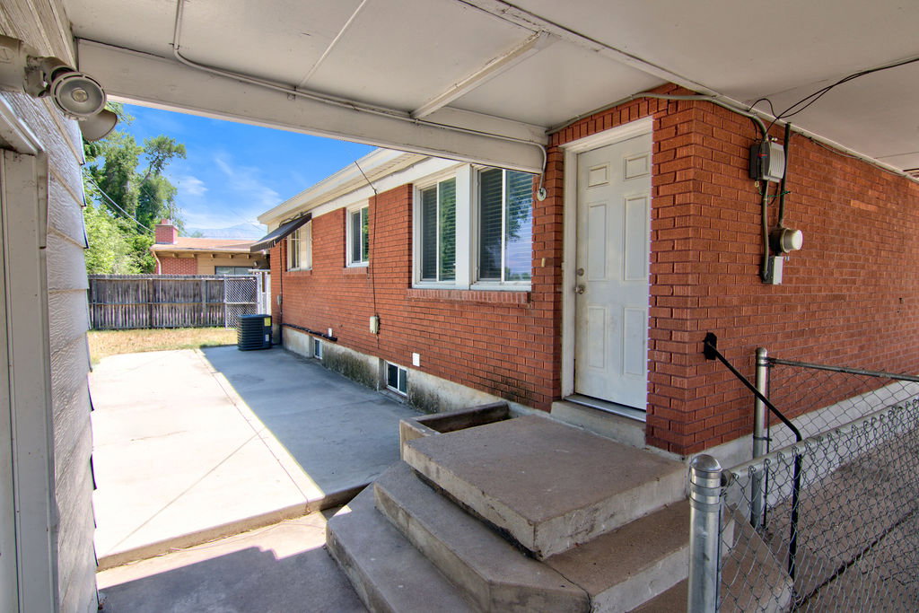Covered patio area featuring a concrete surface, exterior floodlights, and direct access to the brick-sided residence