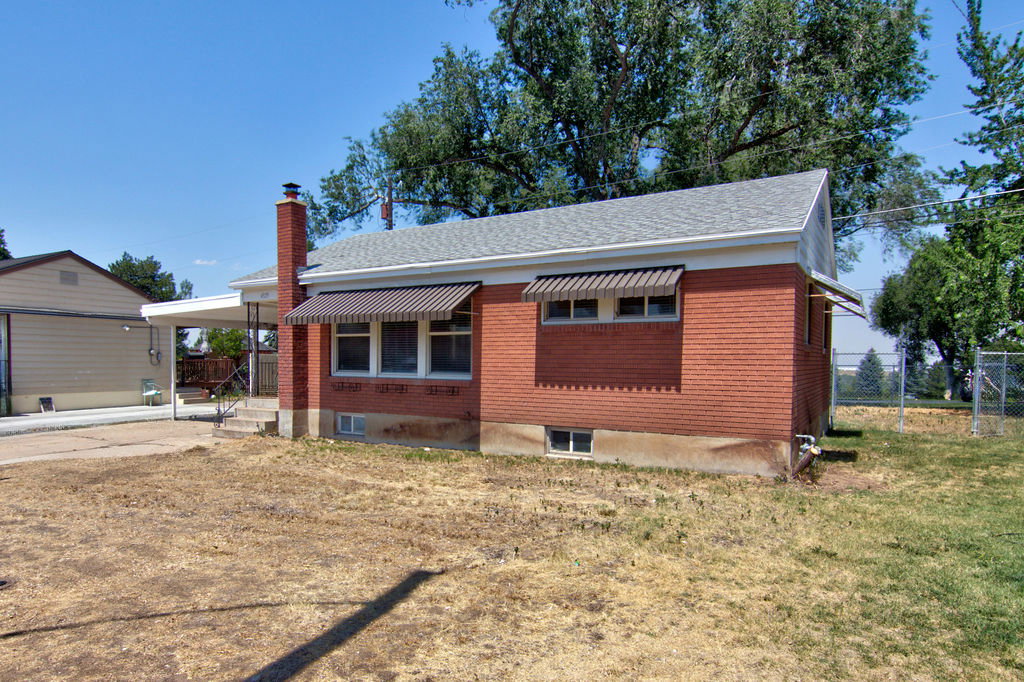 Brick exterior featuring a gabled roof and striped window awnings