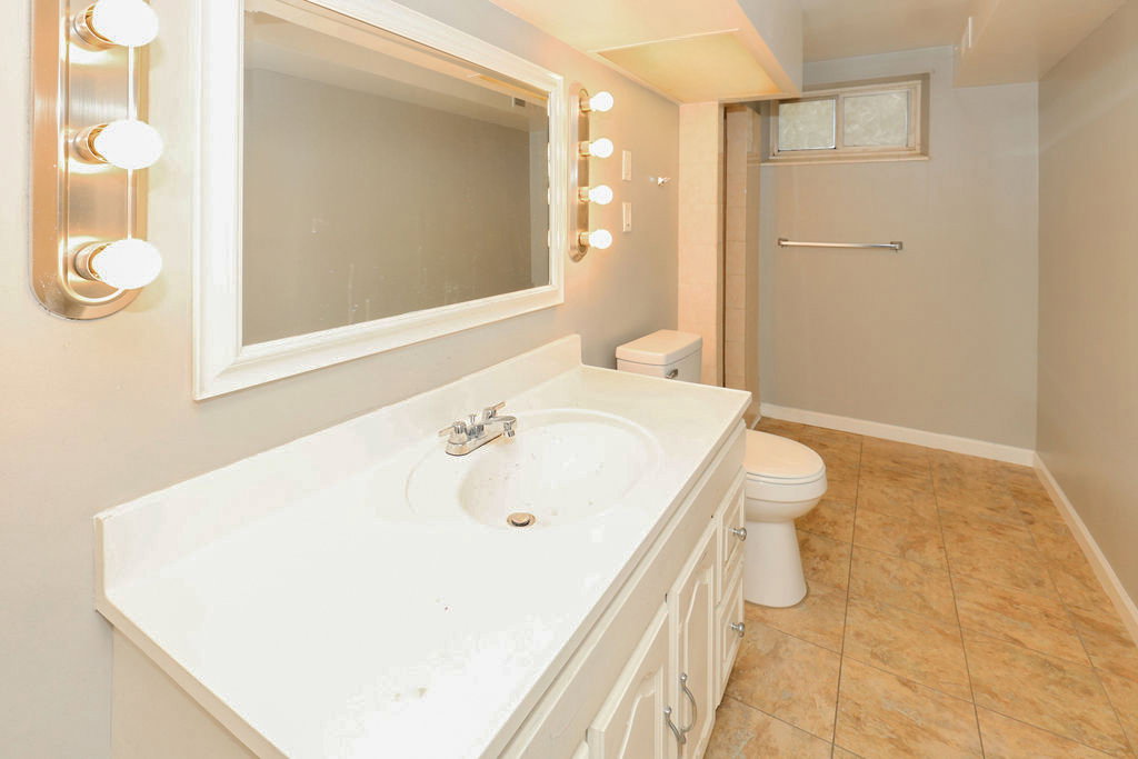 Bathroom featuring a single vanity with an integrated sink, polished chrome faucet, built-in mirror, and tiled flooring