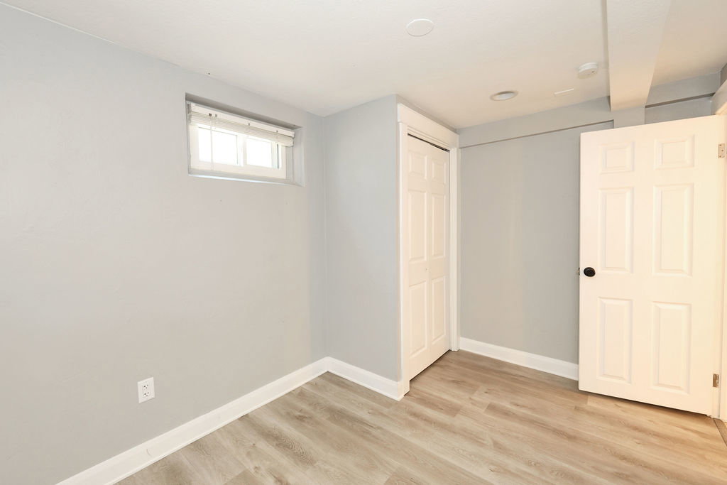 Room featuring light gray walls, wood-finish flooring, a white trim package, and a window with blinds