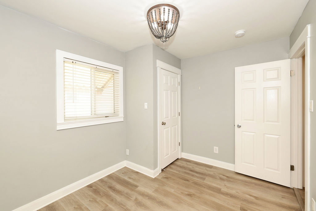 Room featuring wood-finish flooring, light gray walls, and white trim