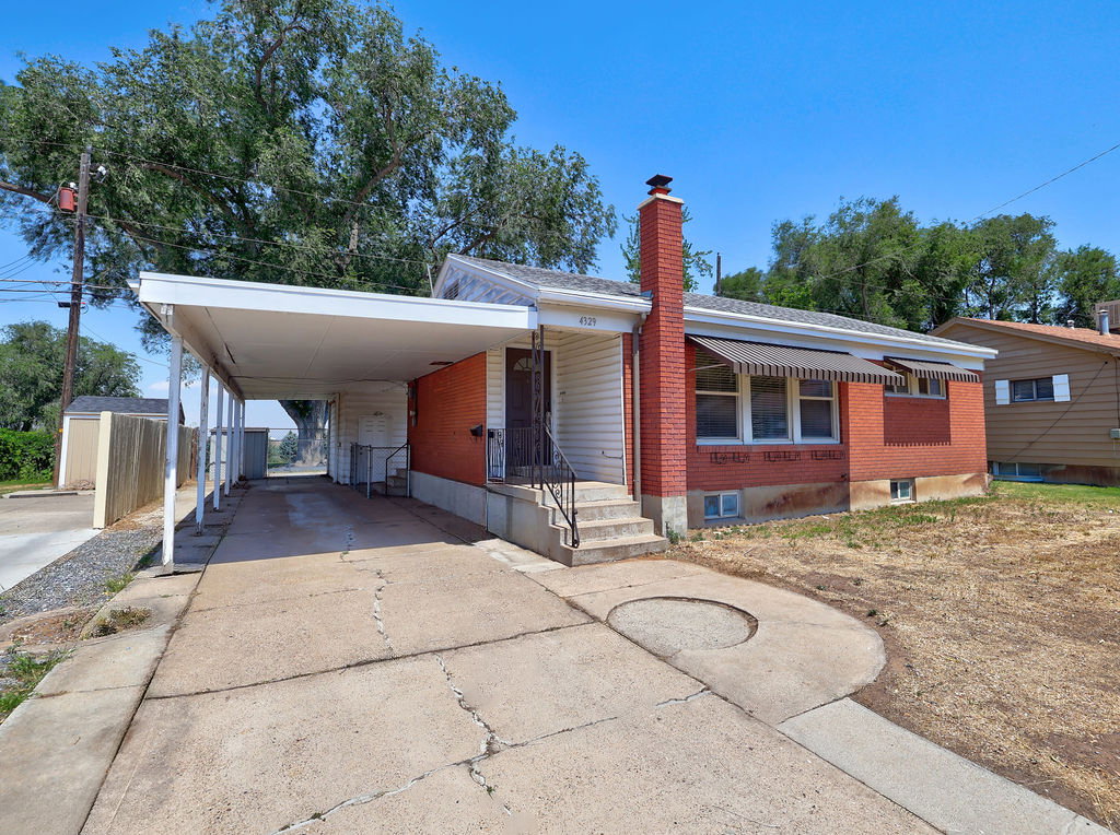 Brick exterior featuring a covered carport, concrete driveway, and front entryway steps