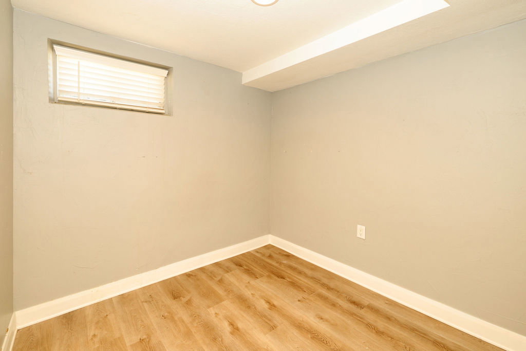 Room with wood-finish flooring, light gray painted walls, and white trim