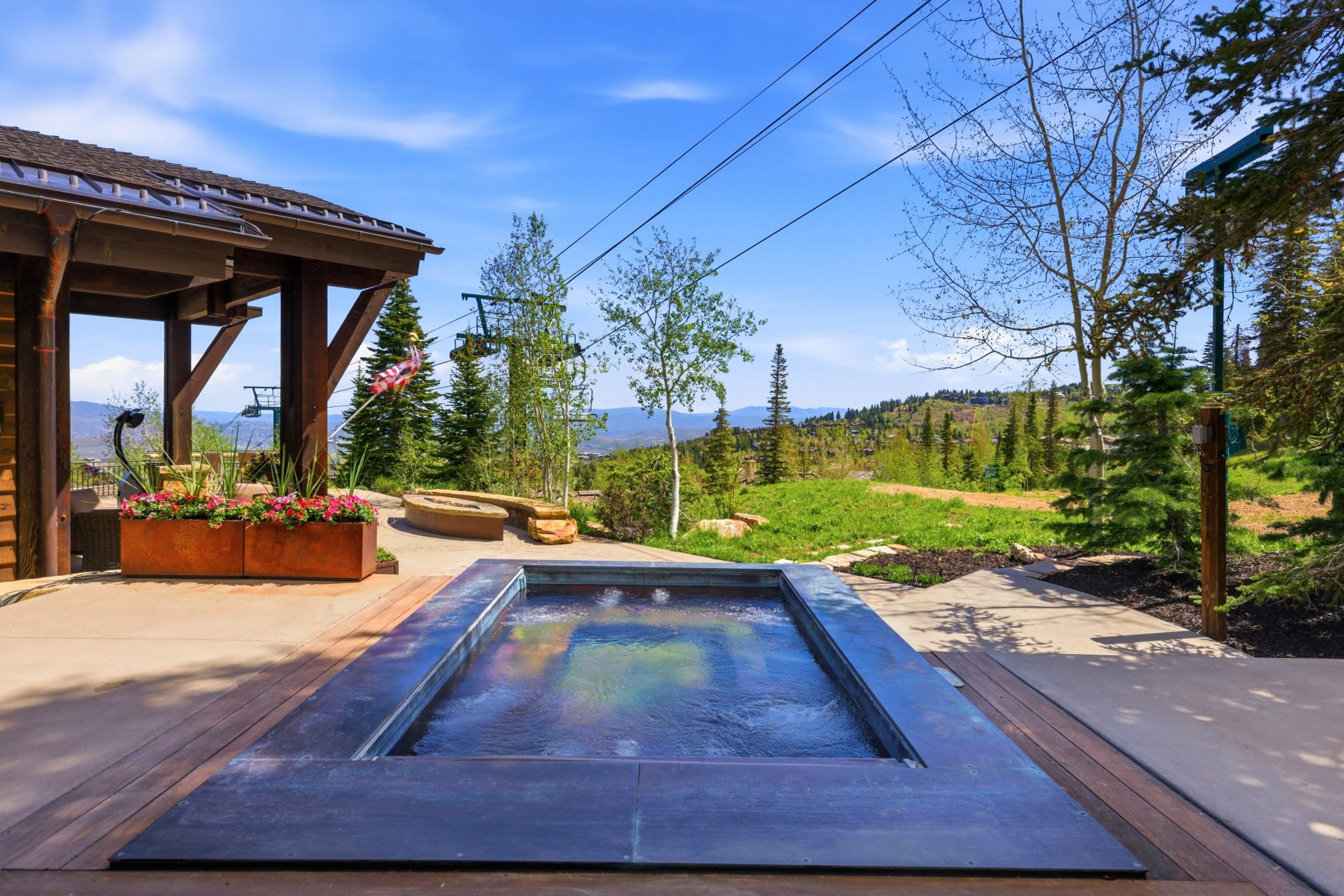 Outdoor spa with dark surround, integrated into a patio featuring concrete and wood-finish decking