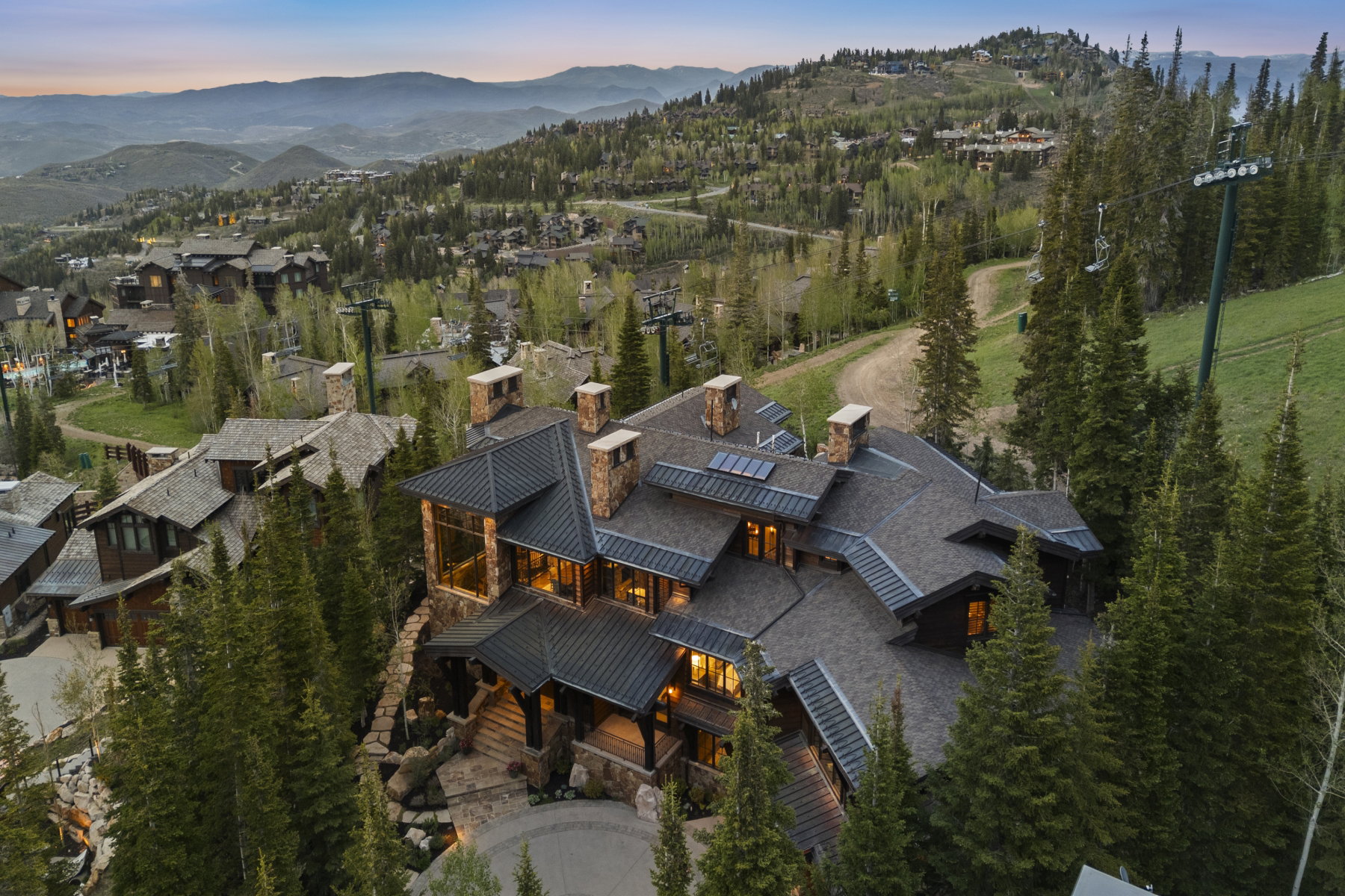 Stone and timber home featuring multiple gabled roofs with dark shingles and metal accents