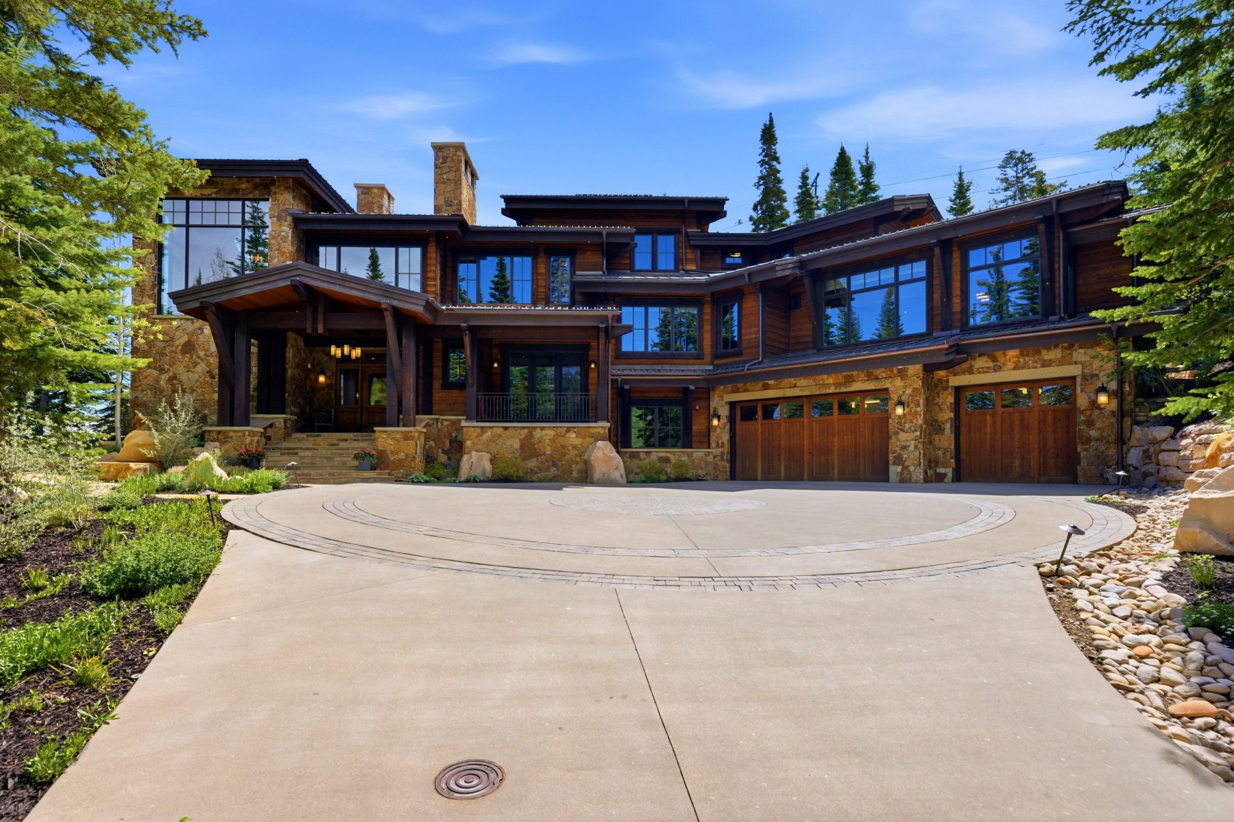 Expansive exterior featuring stone and wood siding, a grand entry with an overhead fixture, and multiple large windows