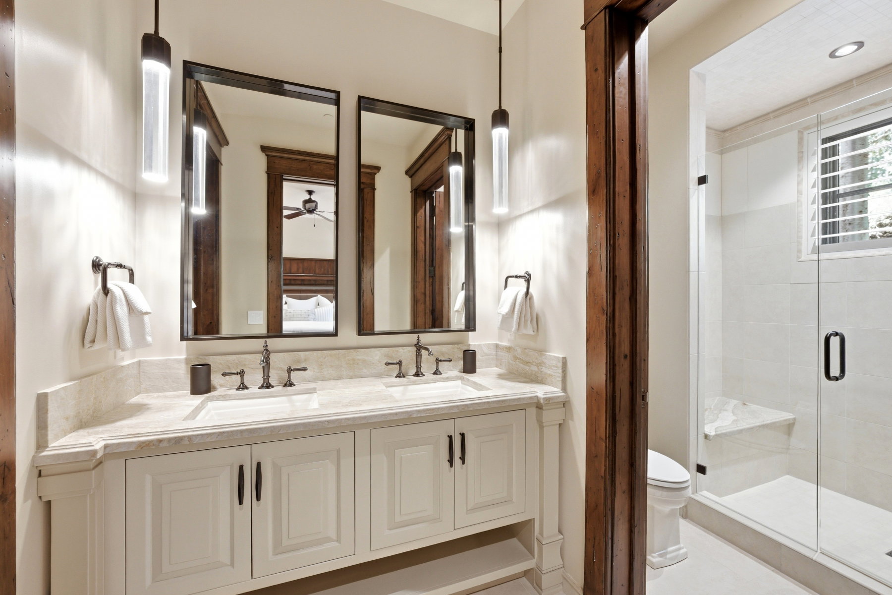 Dual vanity with light-toned stone countertop, integrated sinks, and individual matte black framed mirrors