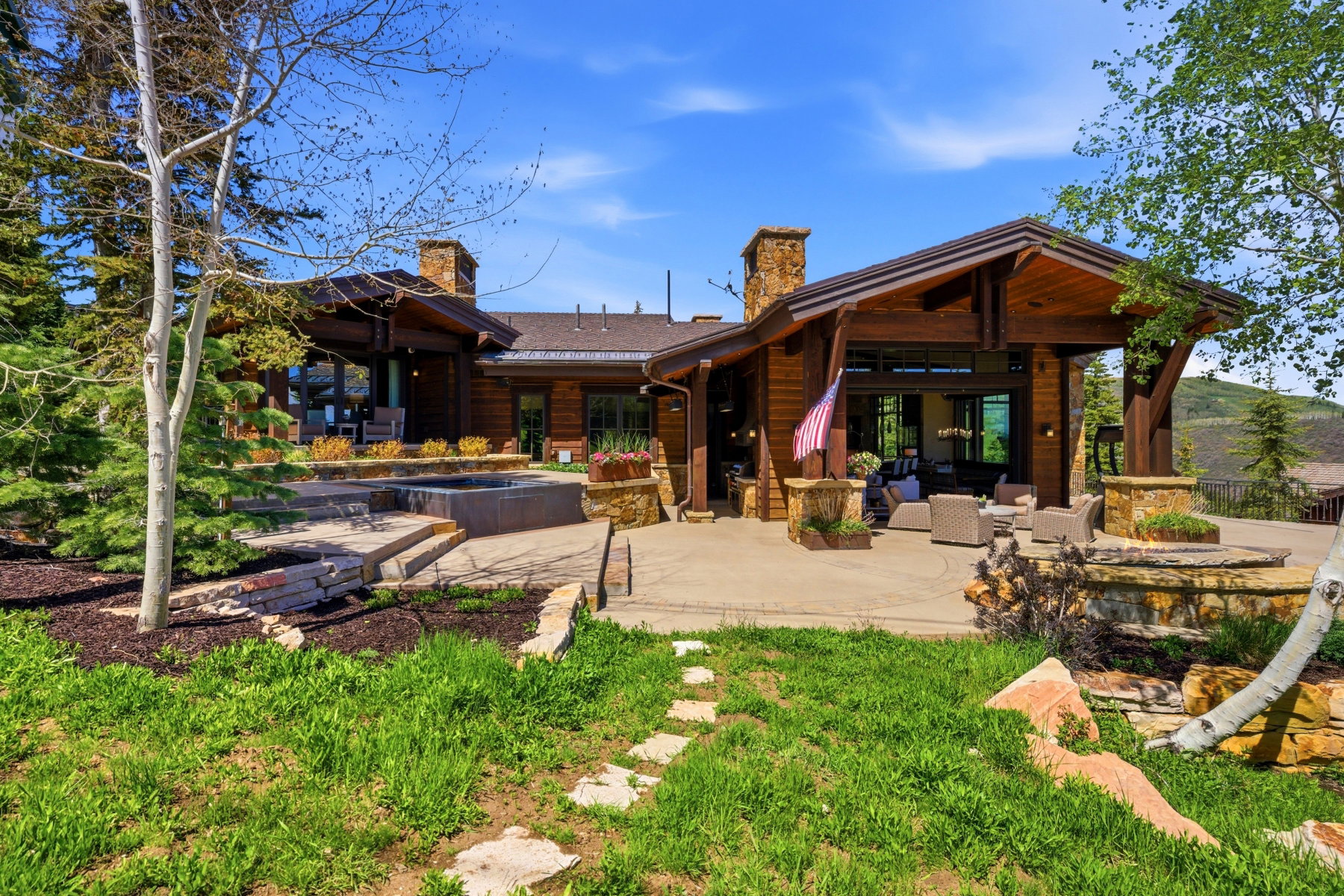 Expansive patio with an integrated spa, stone chimney, and covered outdoor living space