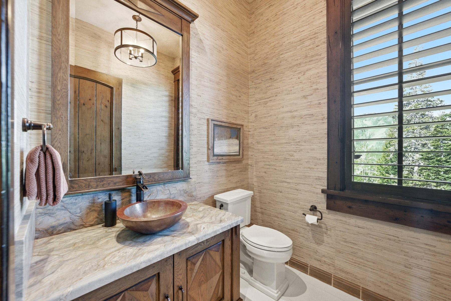 Powder room featuring a custom wood vanity with a stone countertop, vessel sink, and an expansive wood-framed mirror