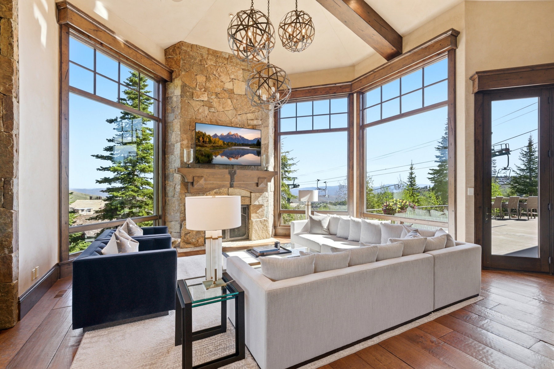Open living space featuring a stone-clad fireplace and expansive window walls