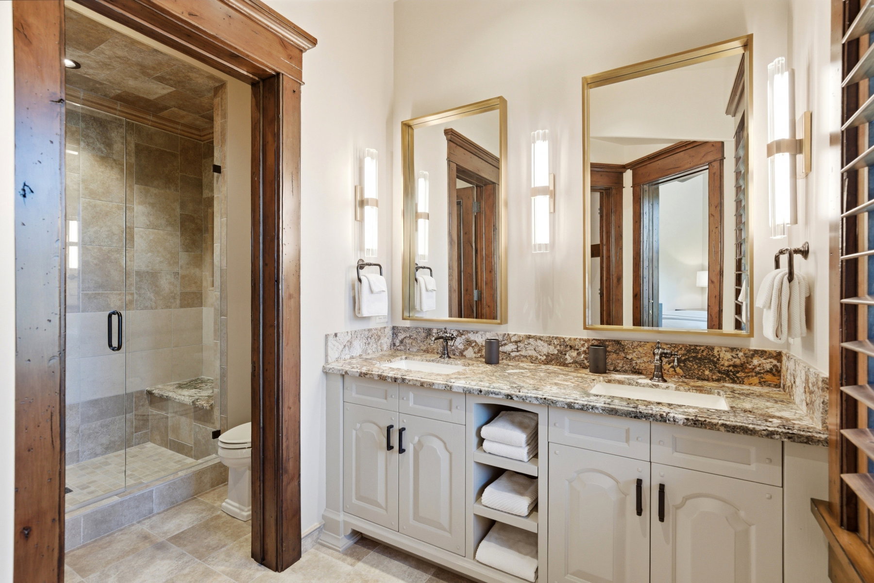 Dual vanity with patterned stone countertop, undermount sinks, and gold-framed mirrors