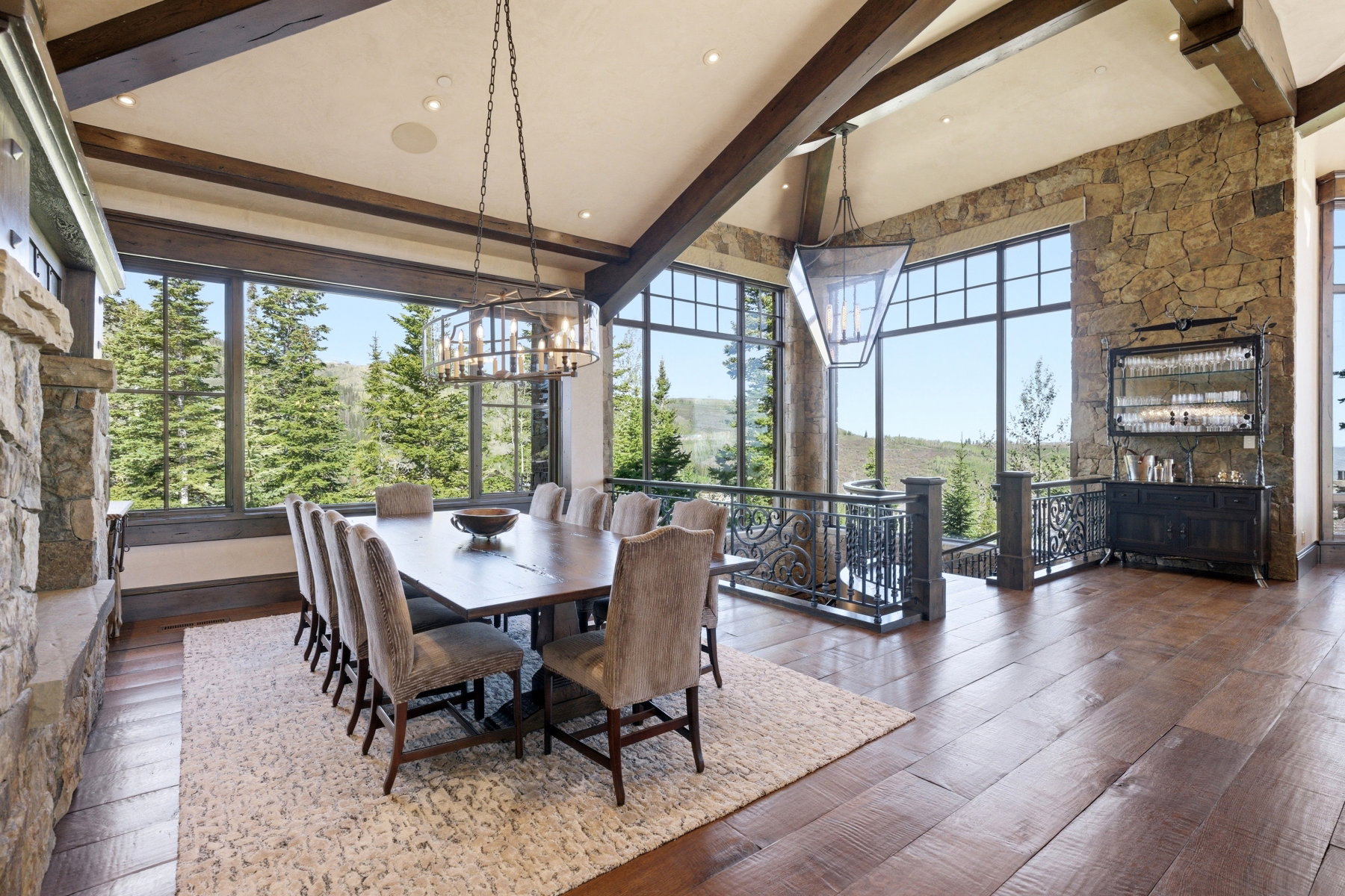 Spacious dining area featuring wood-finish flooring, a stone accent wall, and exposed wood ceiling beams