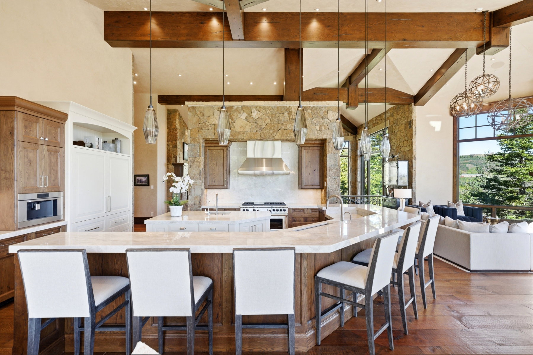 Gourmet kitchen with an expansive island featuring a light-toned countertop, integrated appliances, and stone wall accents
