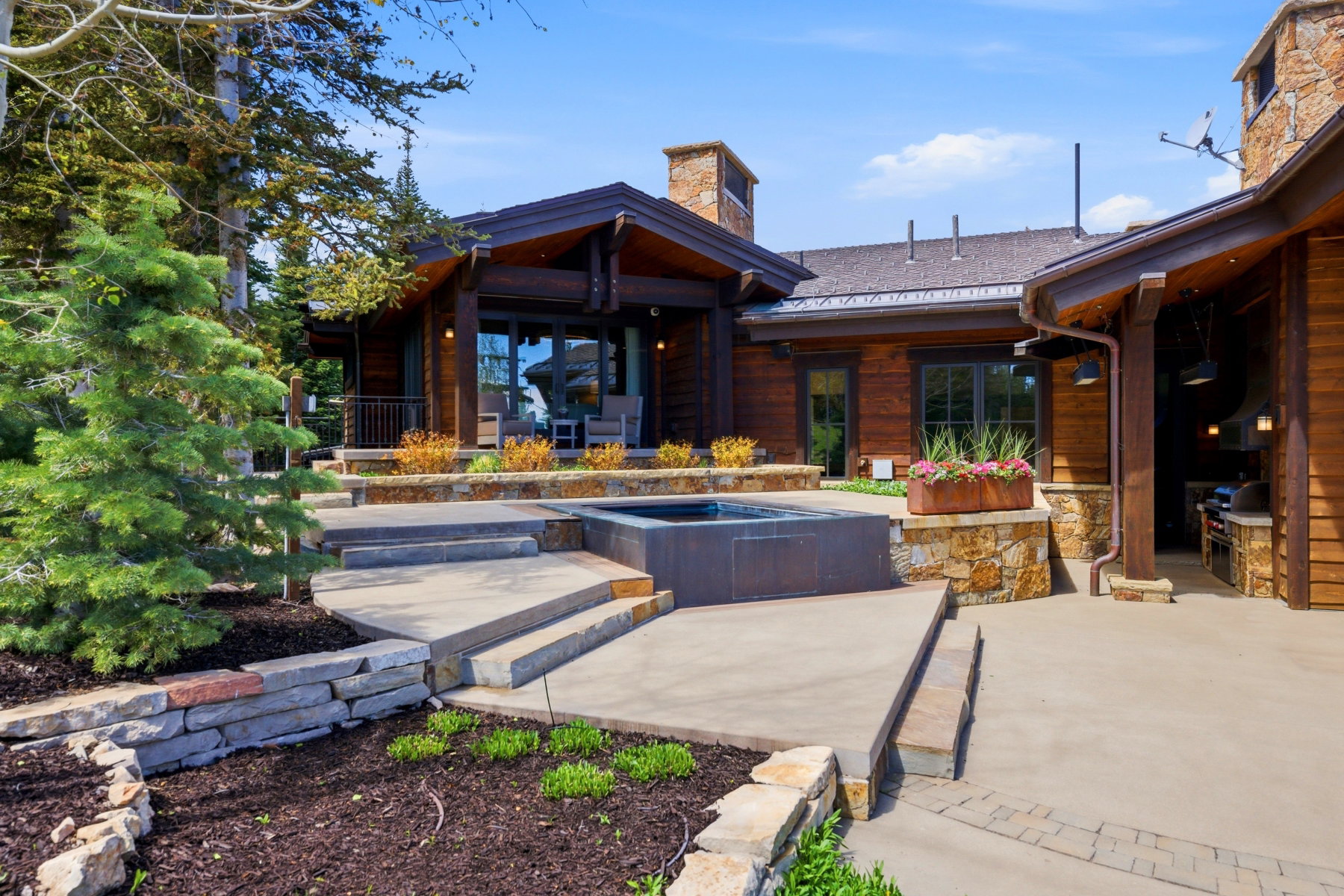 Expansive patio featuring a built-in spa, tiered concrete steps, and stone retaining walls