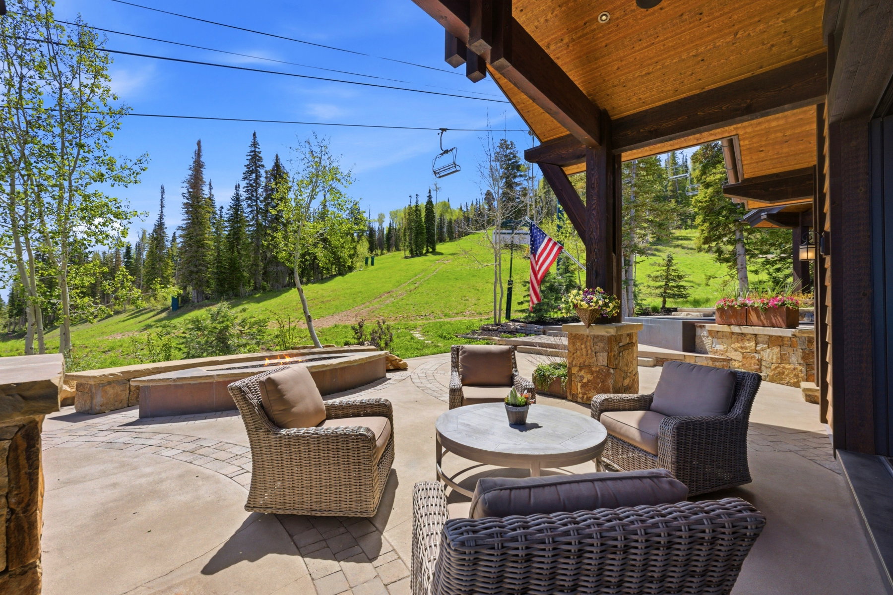 Outdoor covered patio with a tongue-and-groove wood ceiling, exposed timber beams, and stone-clad columns