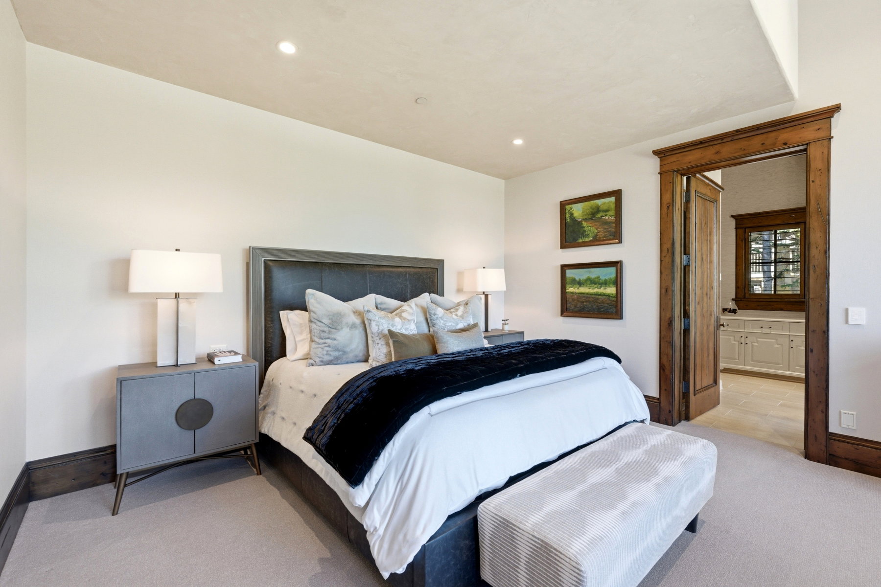 Carpeted room with recessed lighting and a wood-framed doorway leading to an adjacent space with tile flooring and a window