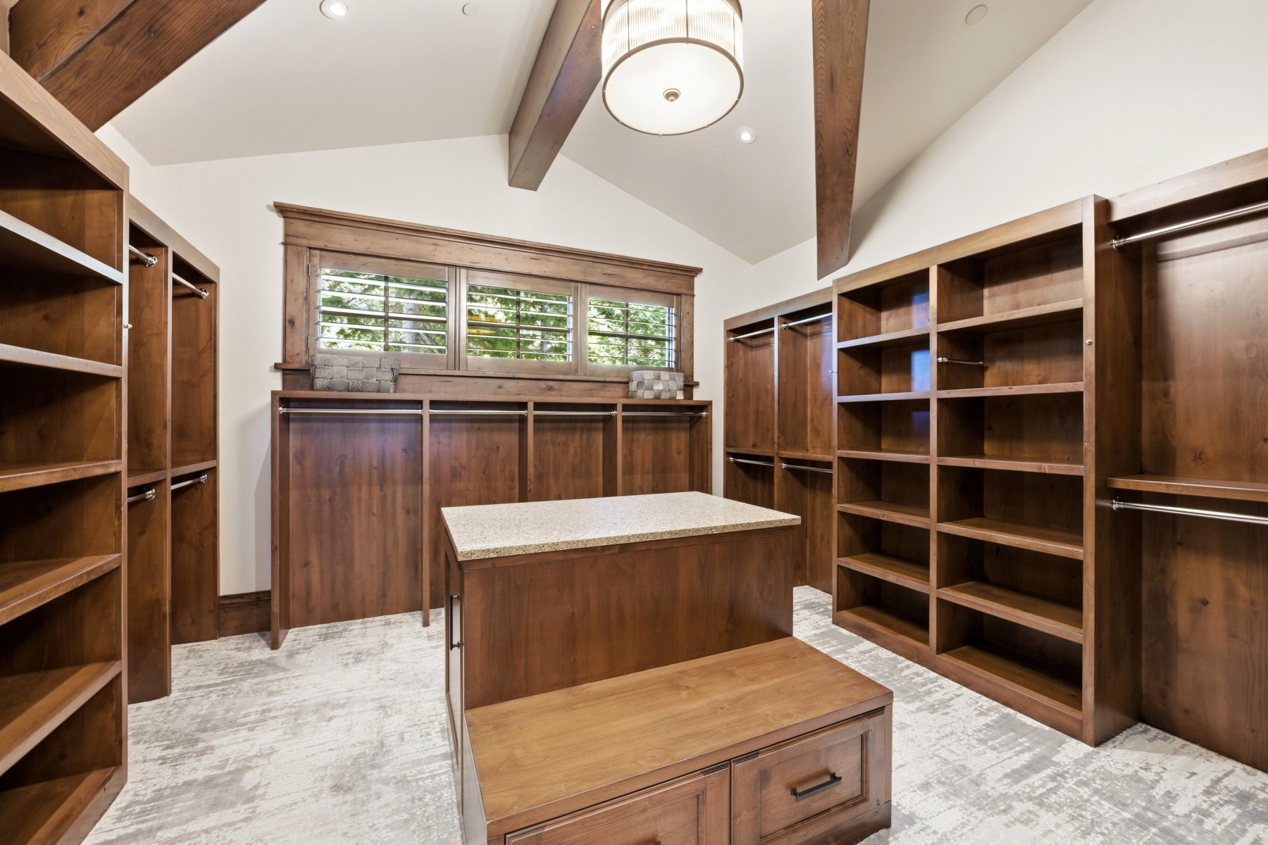 Spacious walk-in closet featuring extensive built-in wood cabinetry, integrated shelving units, and multiple hanging rods