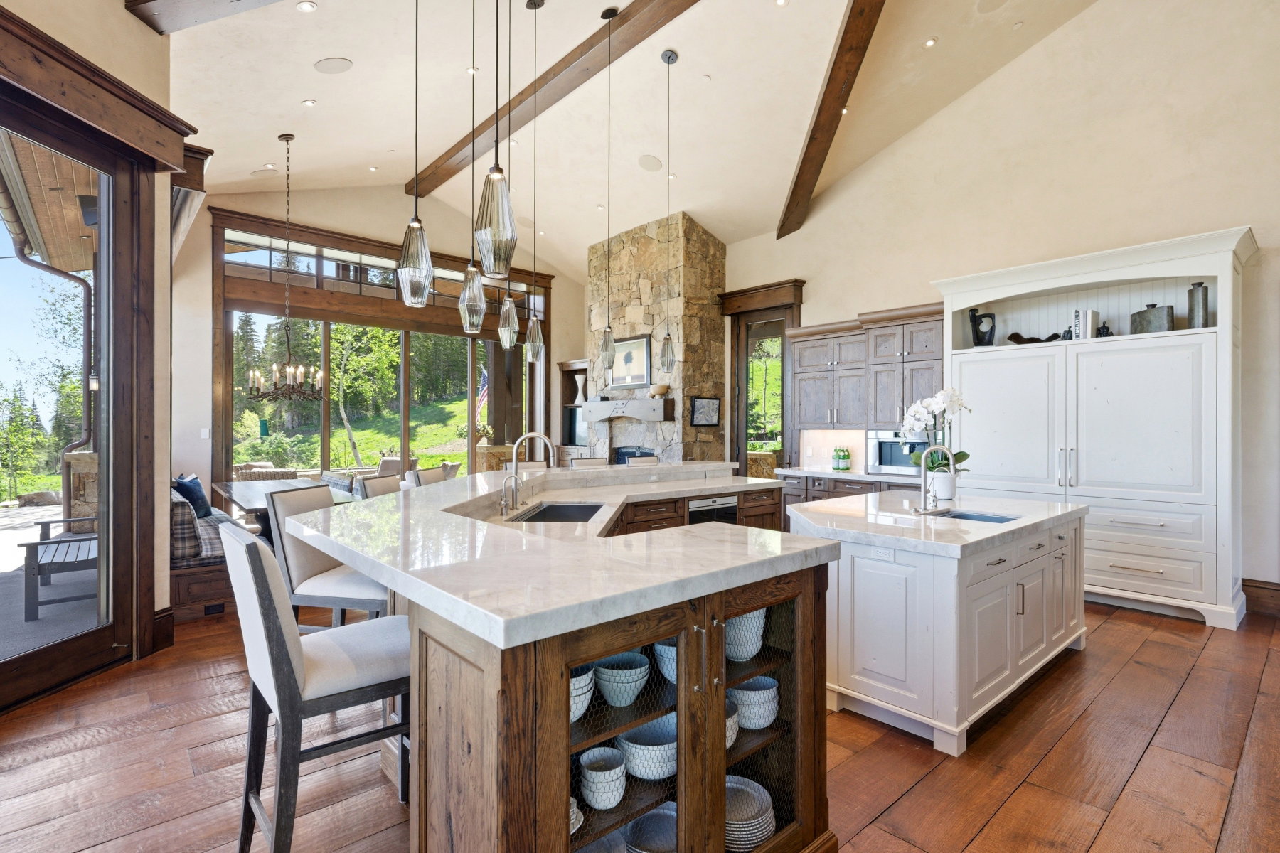 Spacious kitchen featuring wood-finish flooring, vaulted ceilings with exposed beams, and a stone accent wall