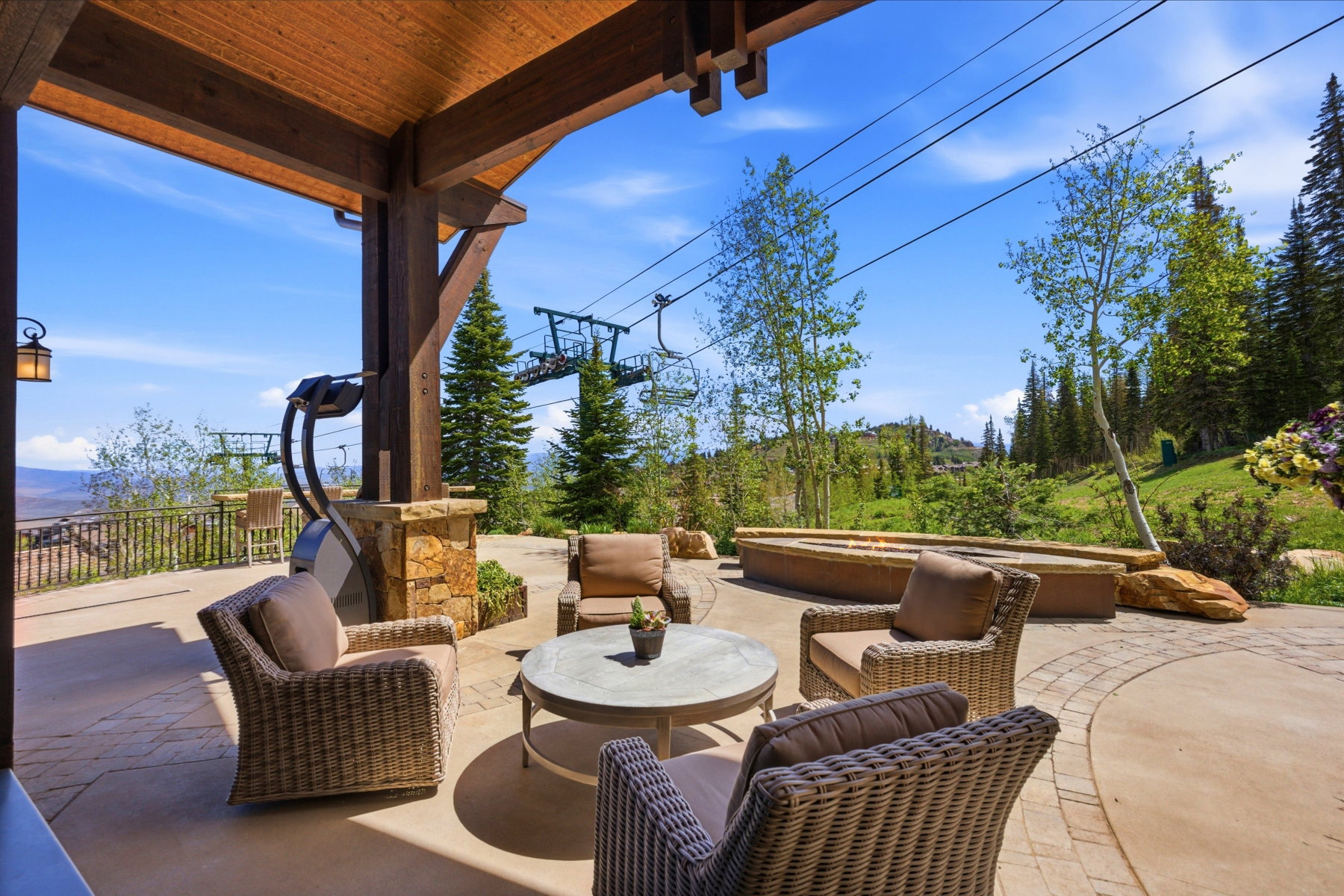 Expansive outdoor patio featuring a wood-beam ceiling, stone-clad columns, and a stamped concrete surface
