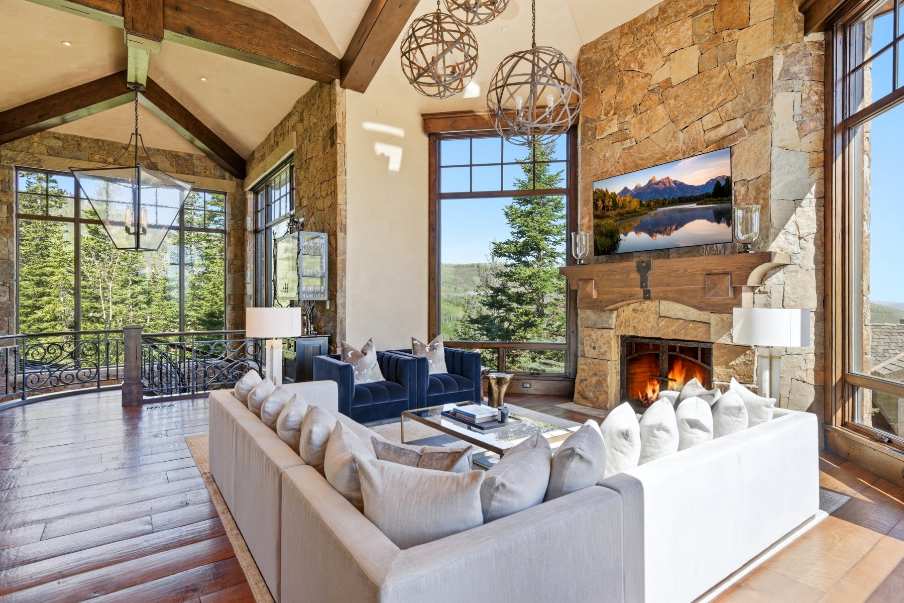 Vaulted ceilings with exposed wood beams frame this living space featuring a stone fireplace with a wood mantel