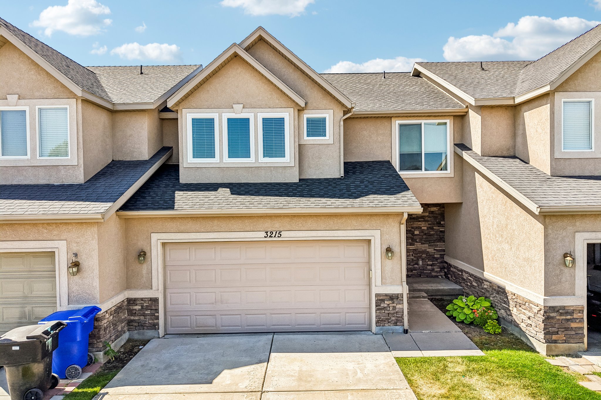 Multi-level townhouse exterior featuring stucco siding and stone veneer accents