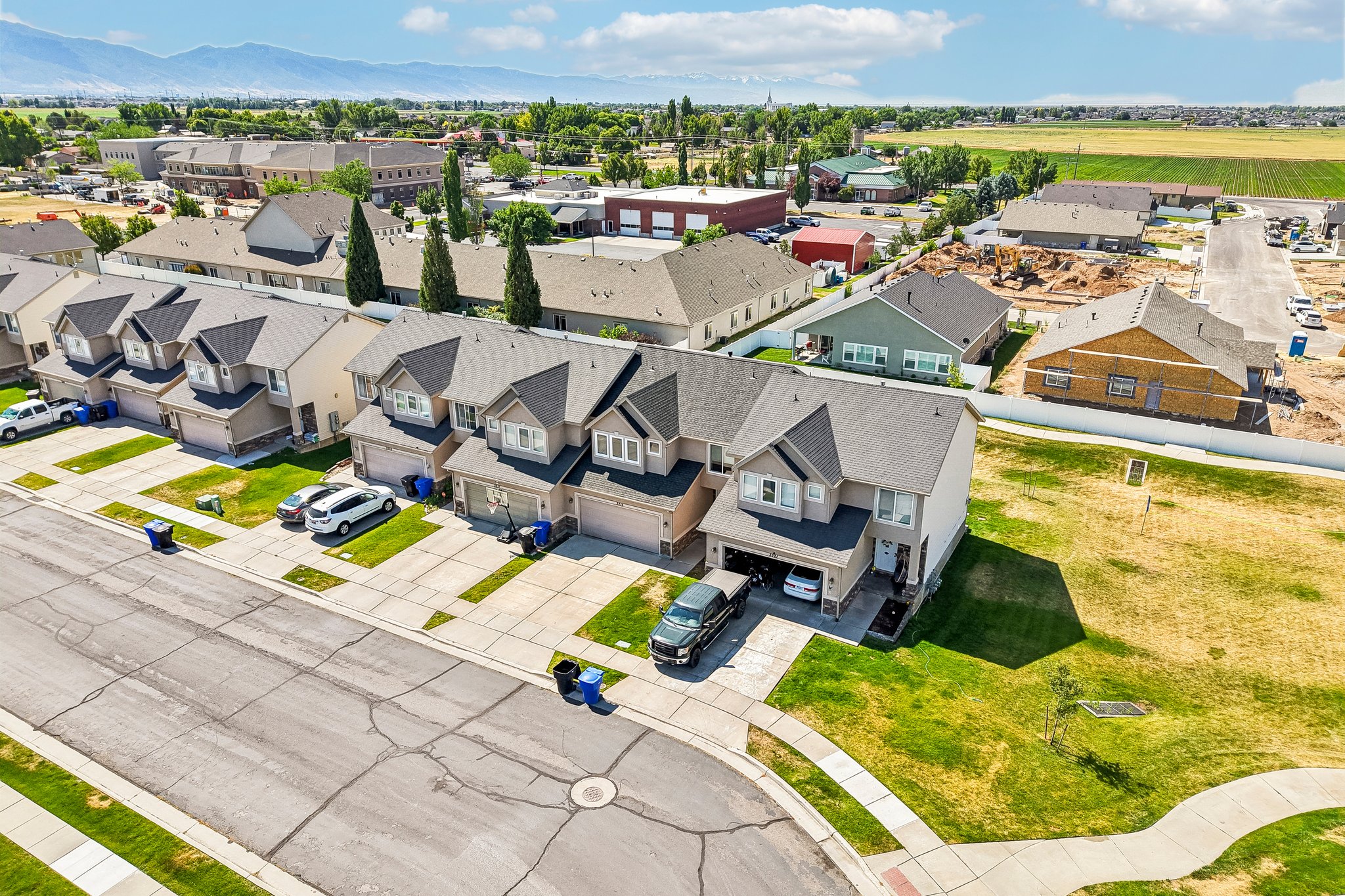 Aerial perspective showcasing a residential street with multiple properties featuring attached garages, concrete driveways, and manicured front lawns