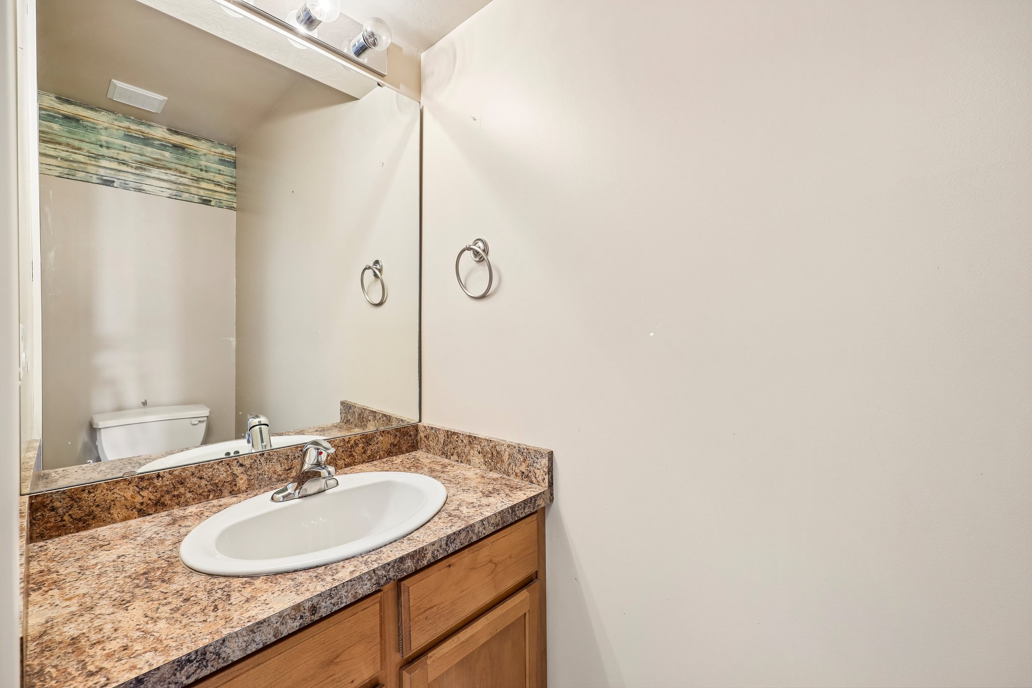Bathroom vanity featuring an oval undermount sink, a chrome faucet, and a patterned countertop