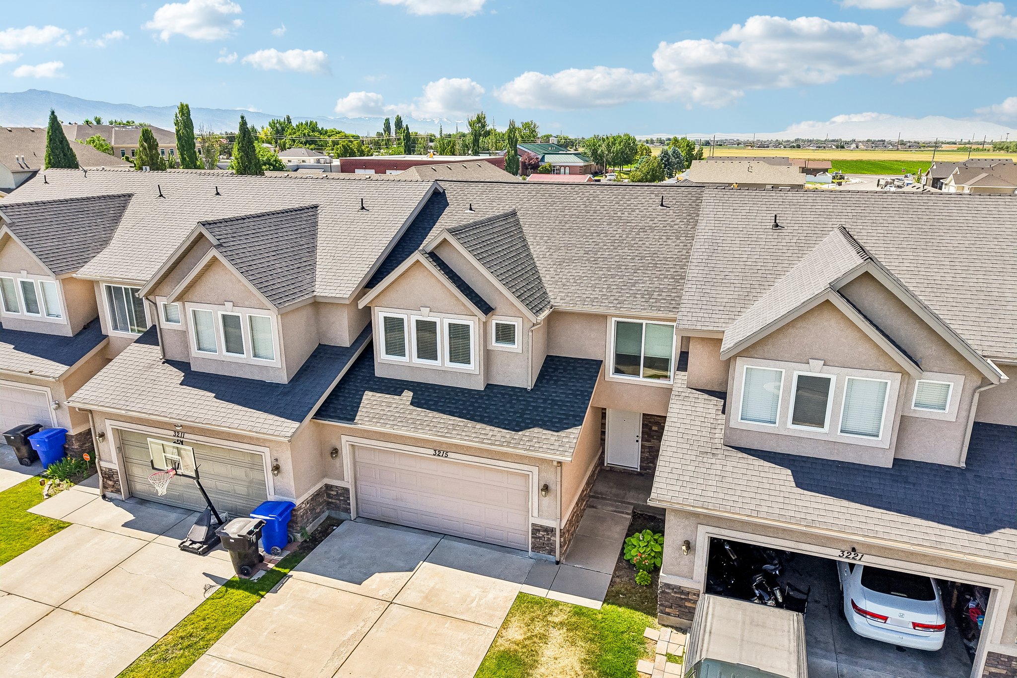 Townhome exterior featuring tan stucco siding and dark shingle roofing