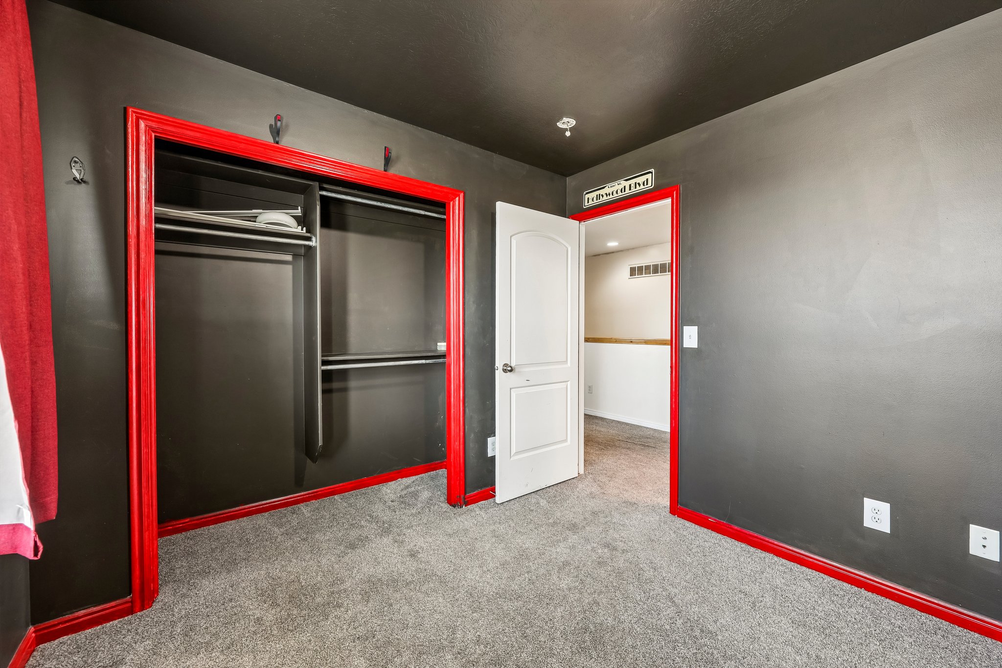 Room featuring dark gray walls, red trim, and gray carpet flooring