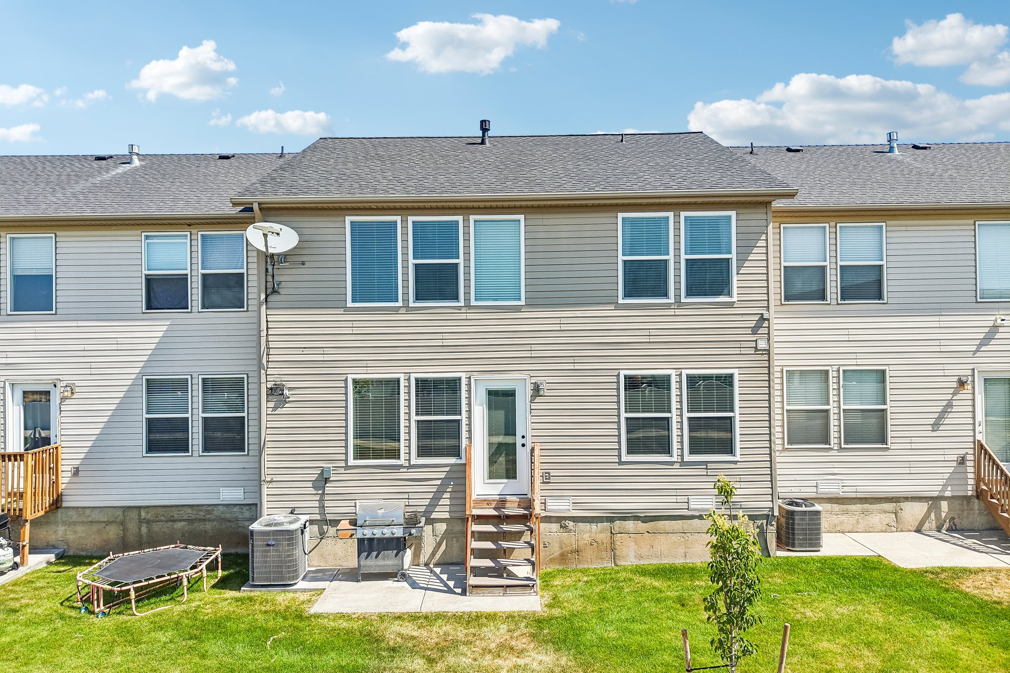 Rear exterior featuring horizontal siding, multiple windows, and a ground-level patio