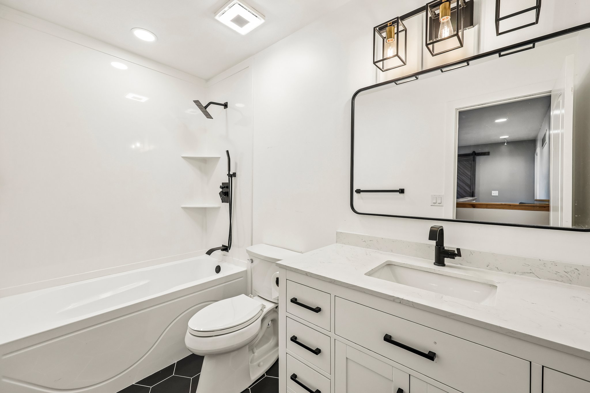 Bathroom featuring a white vanity with an integrated sink, black hardware, and a quartz-finish countertop