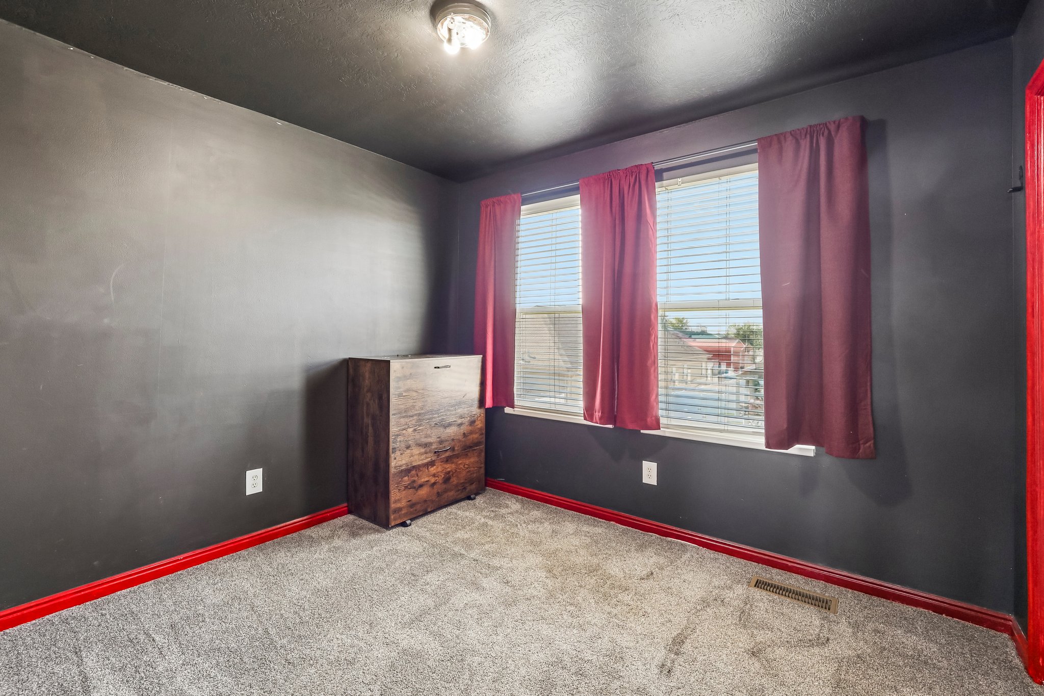 Room featuring dark gray walls, a gray carpeted floor, and red trim
