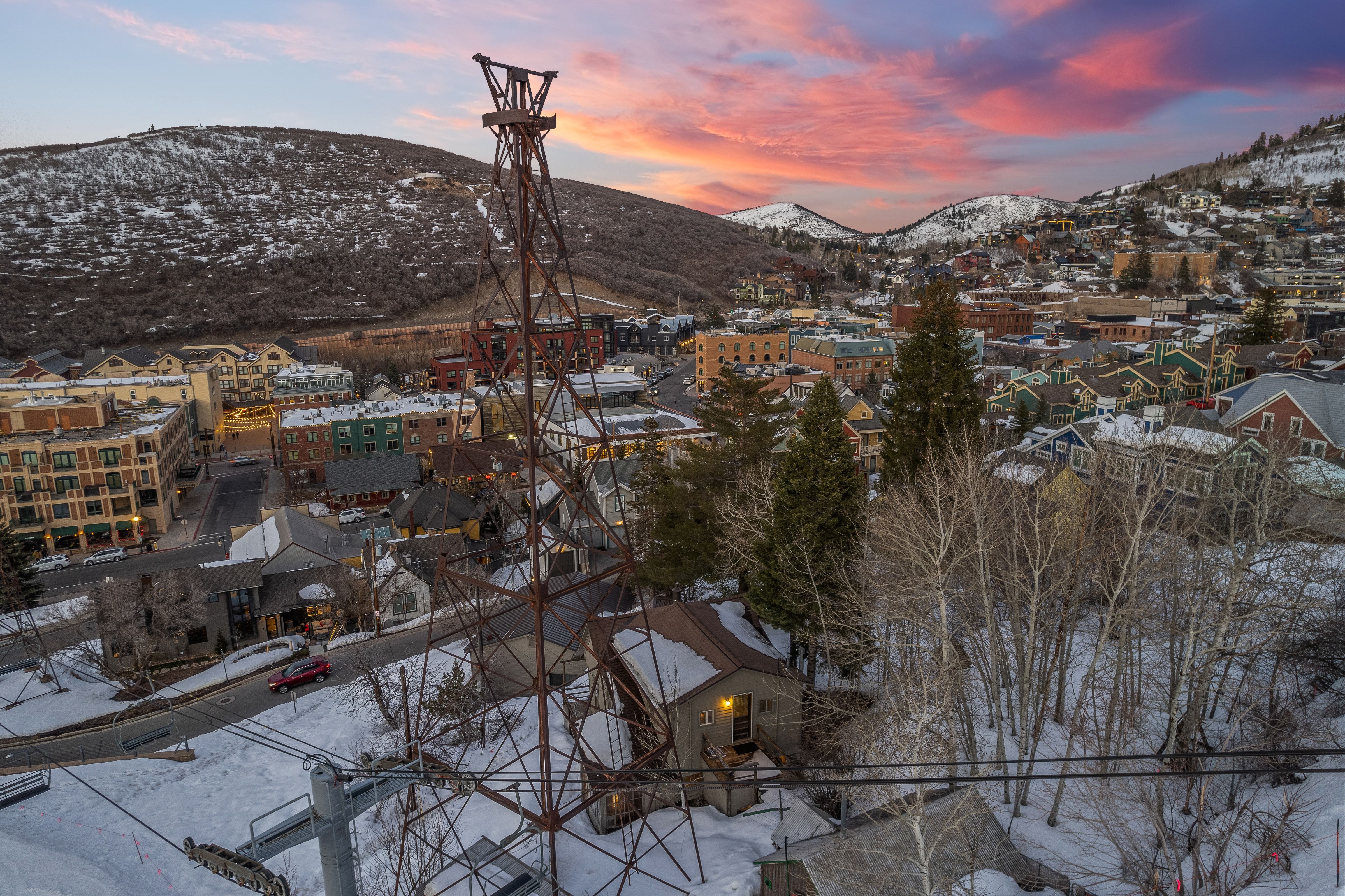 Aerial perspective showcasing a mountain community with diverse architectural styles, snow-covered hillsides, and a prominent mining-era structure