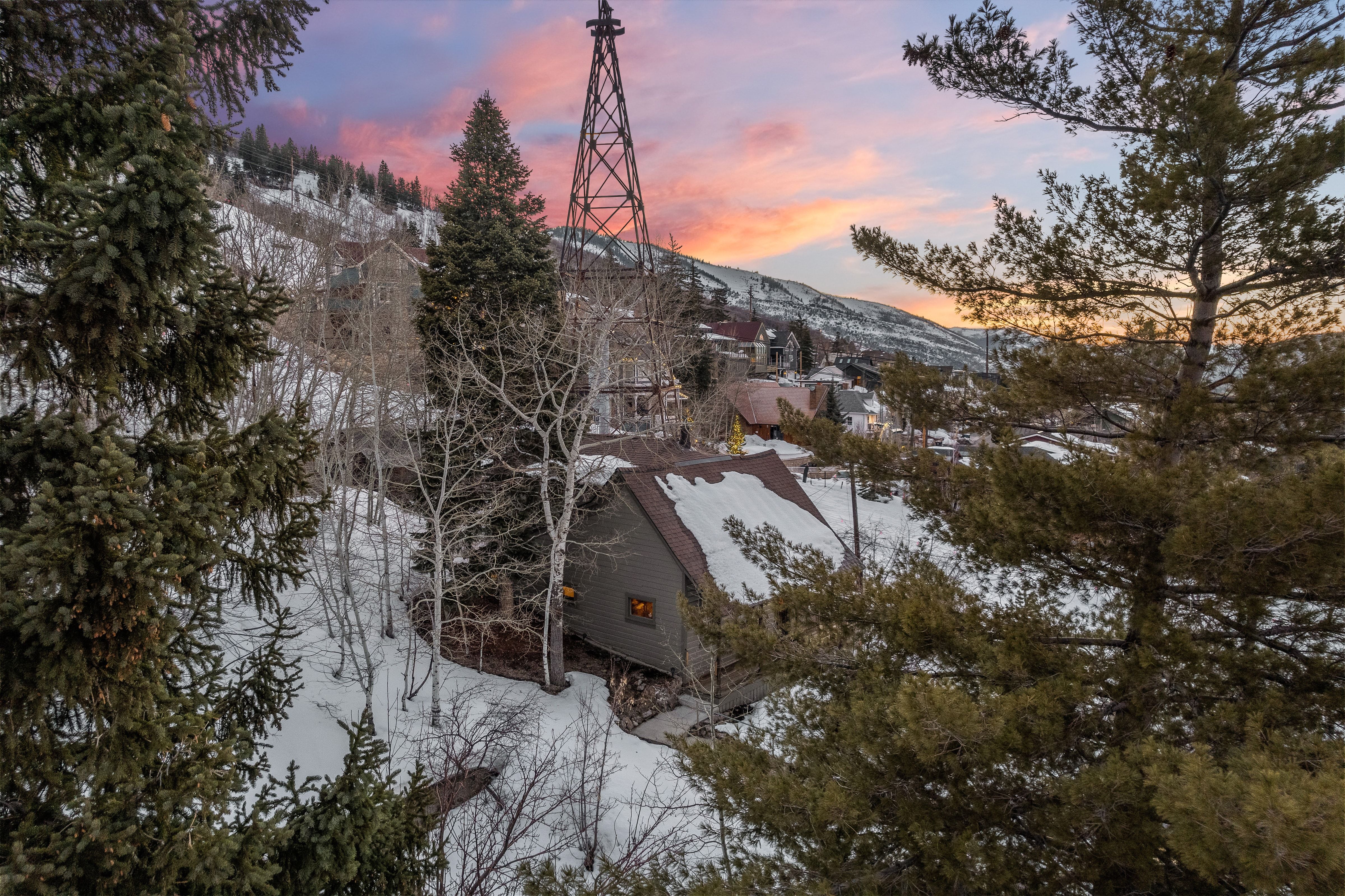 Mountain landscape featuring a distant town, a prominent mining derrick, and evergreen trees