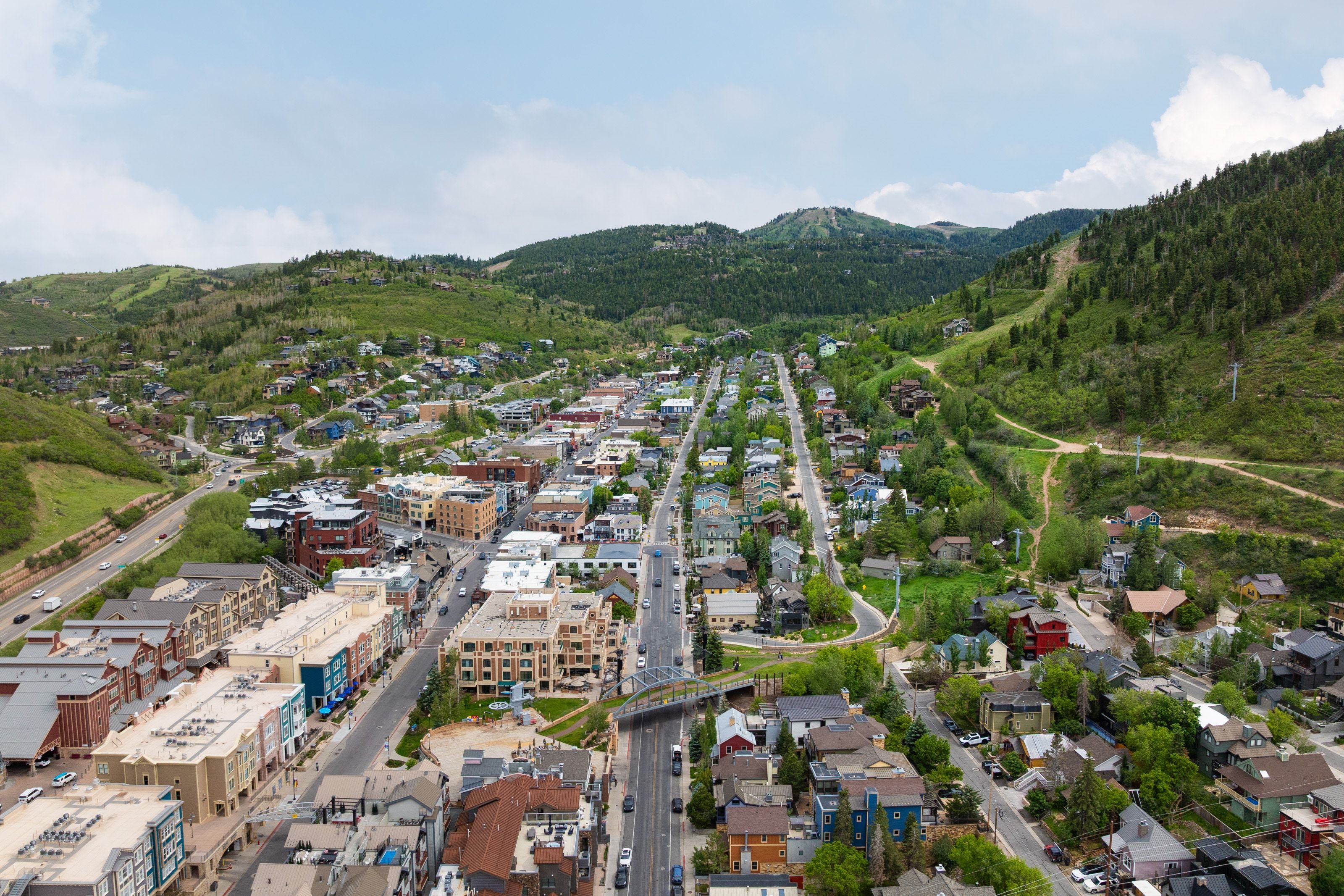Expansive aerial perspective showcasing a vibrant community nestled among verdant, tree-covered mountains