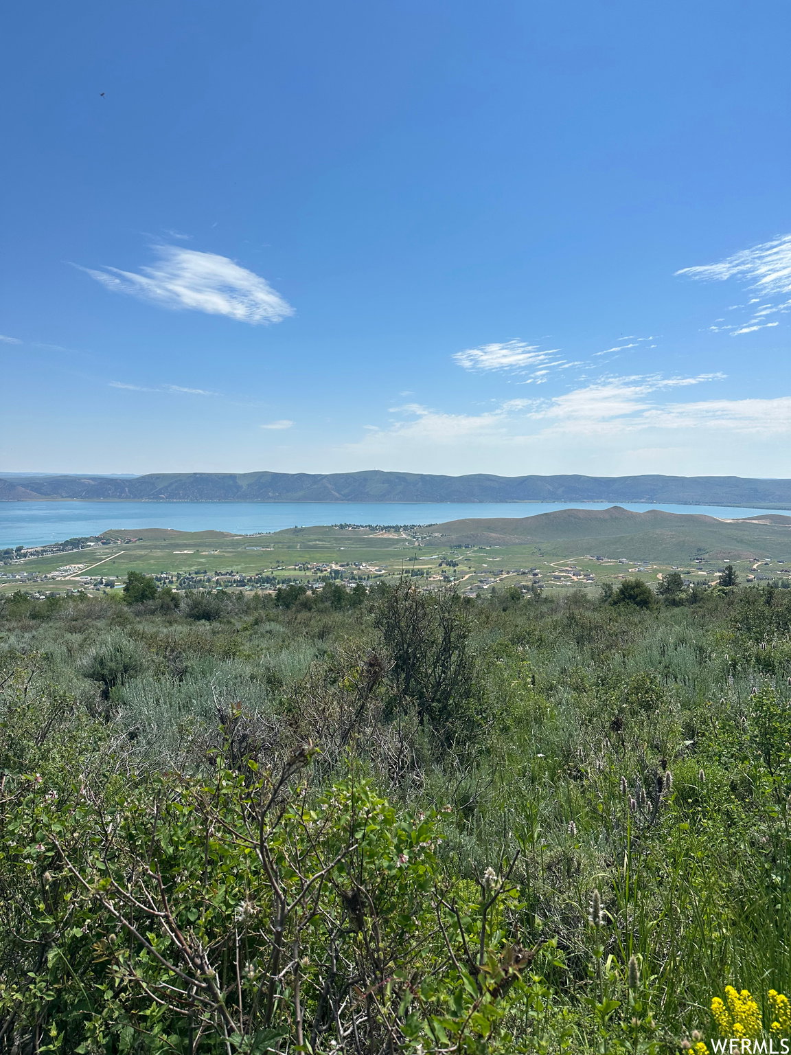 Expansive natural landscape featuring a prominent body of water bordered by distant hills