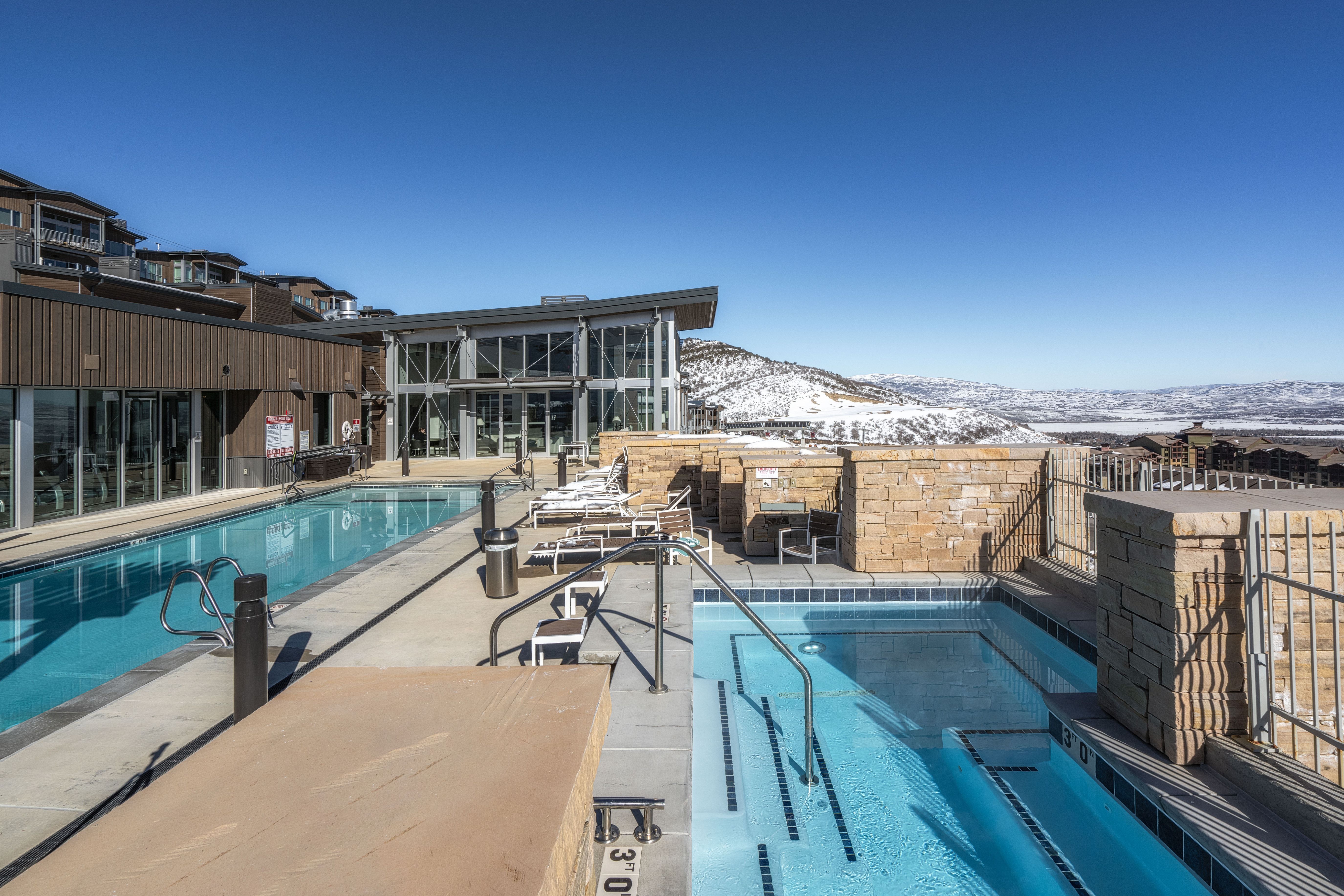 Outdoor aquatic area featuring a rectangular pool and a separate spa